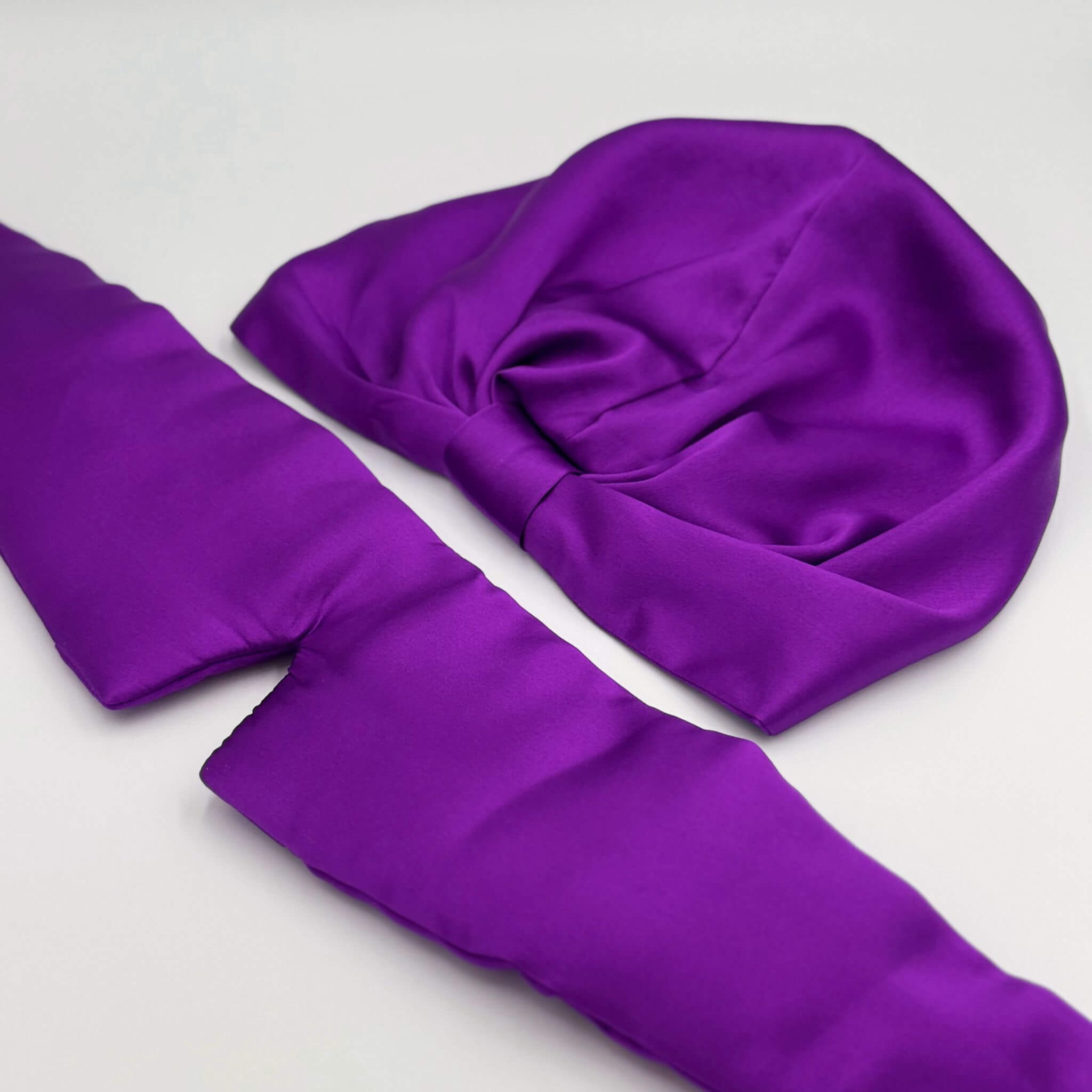 Purple silk bonnet and eye mask set on a light gray background