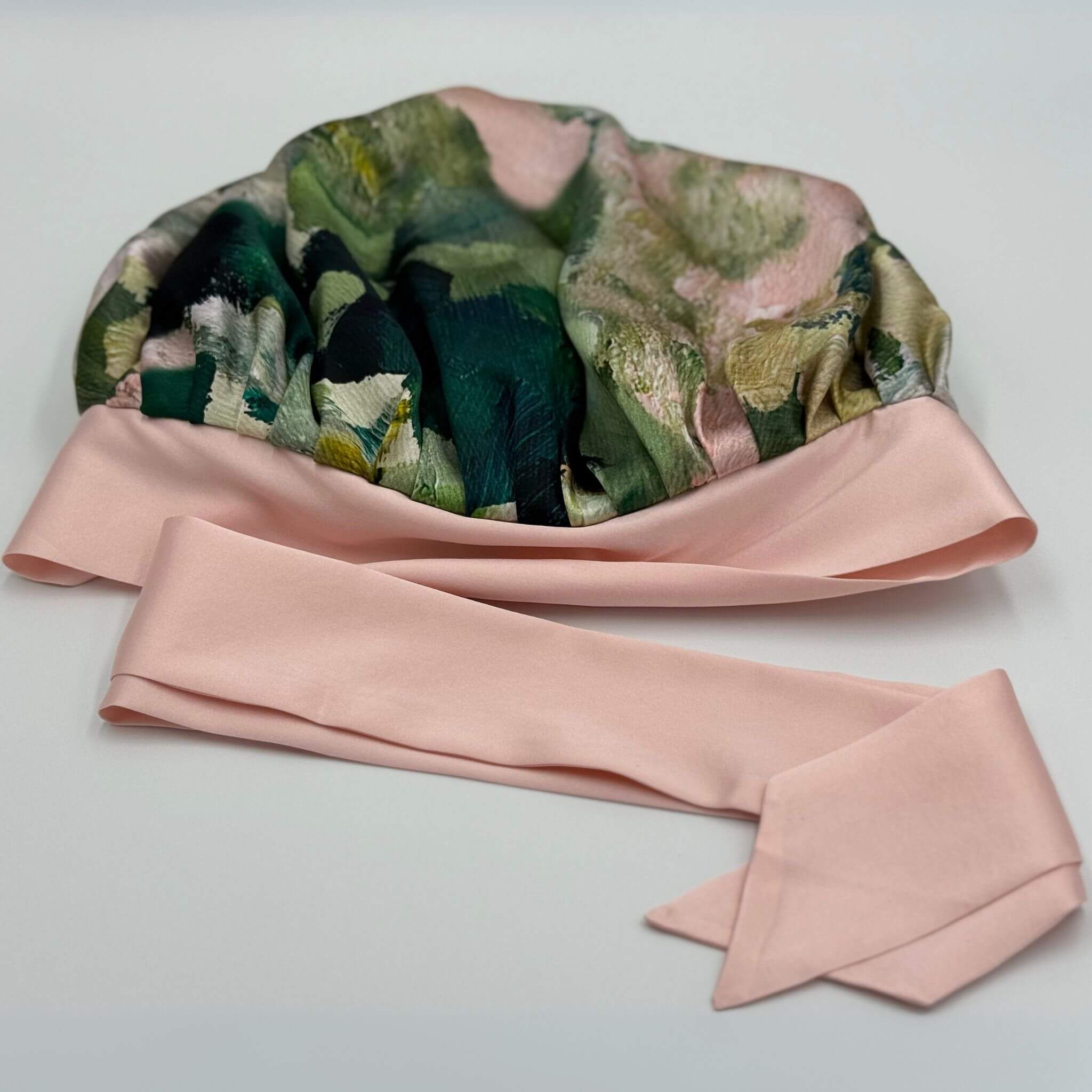 Floral-patterned silk bonnet with a pink bow on a light gray background