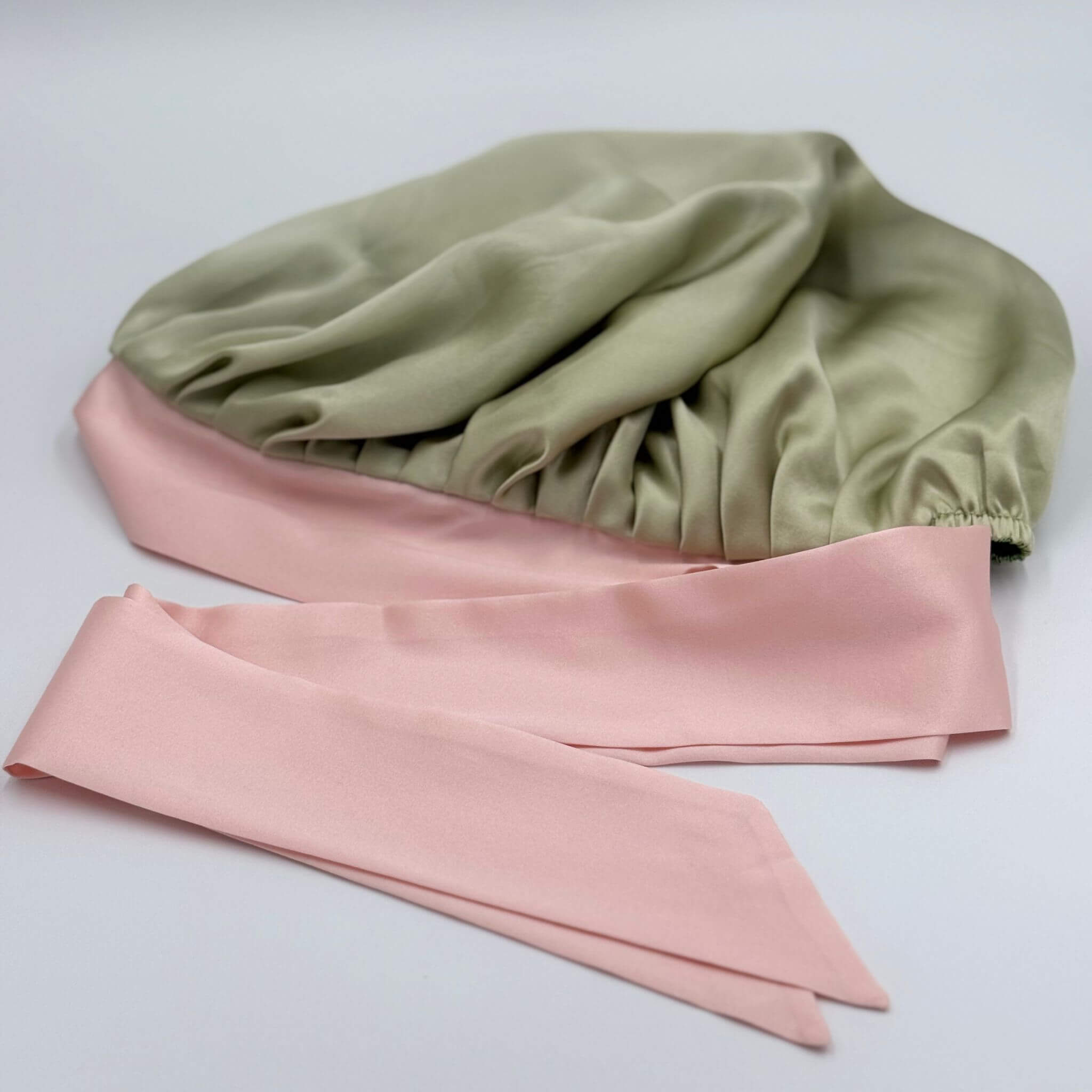 Green and pink silk bonnet on a light gray background
