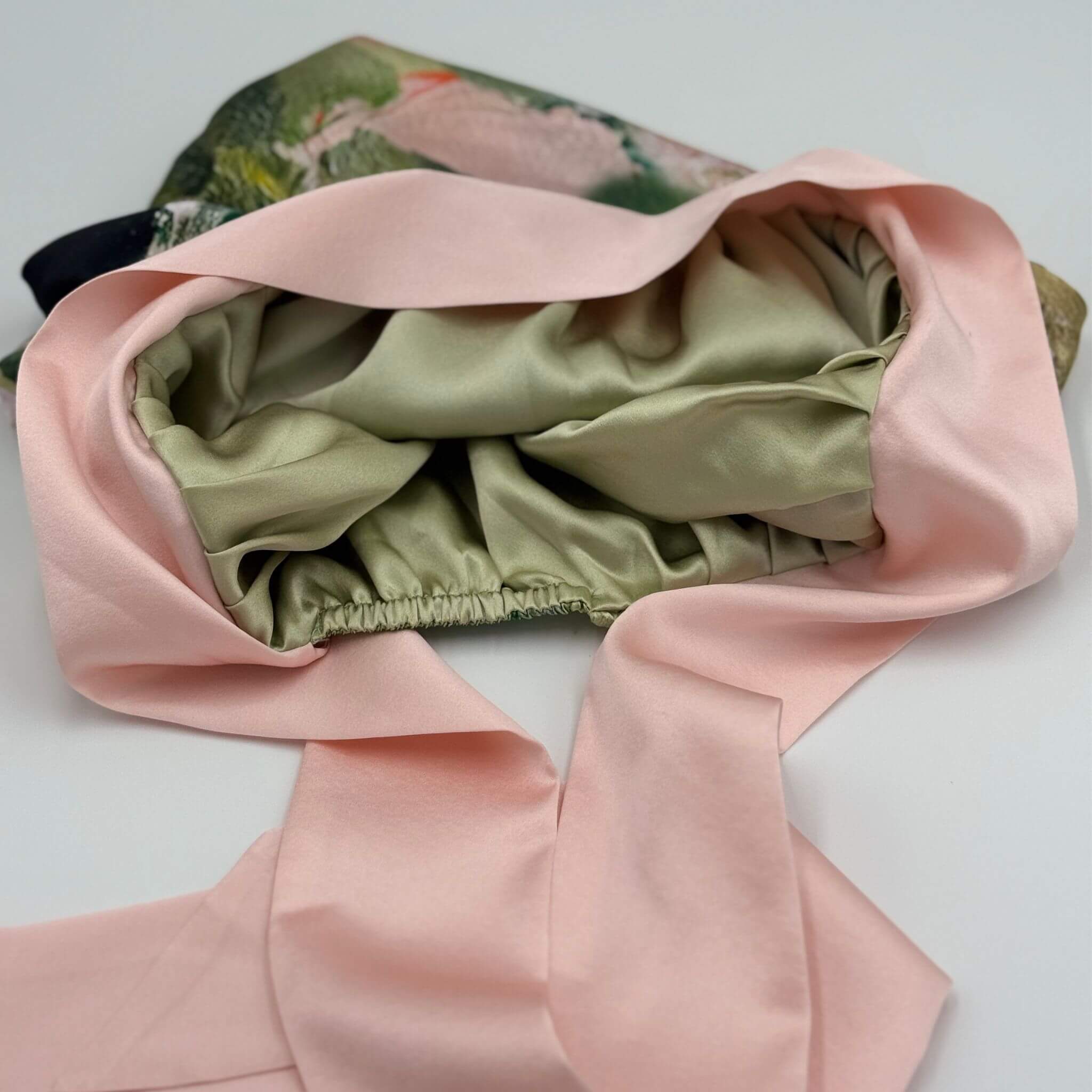 Green silk fabric inside a pink silk bonnet on a light gray background