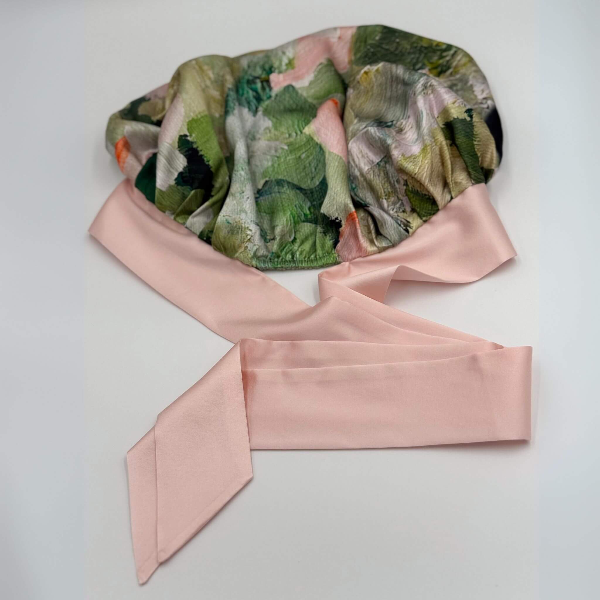 Floral-patterned silk bonnet with a pink ribbon on a white background