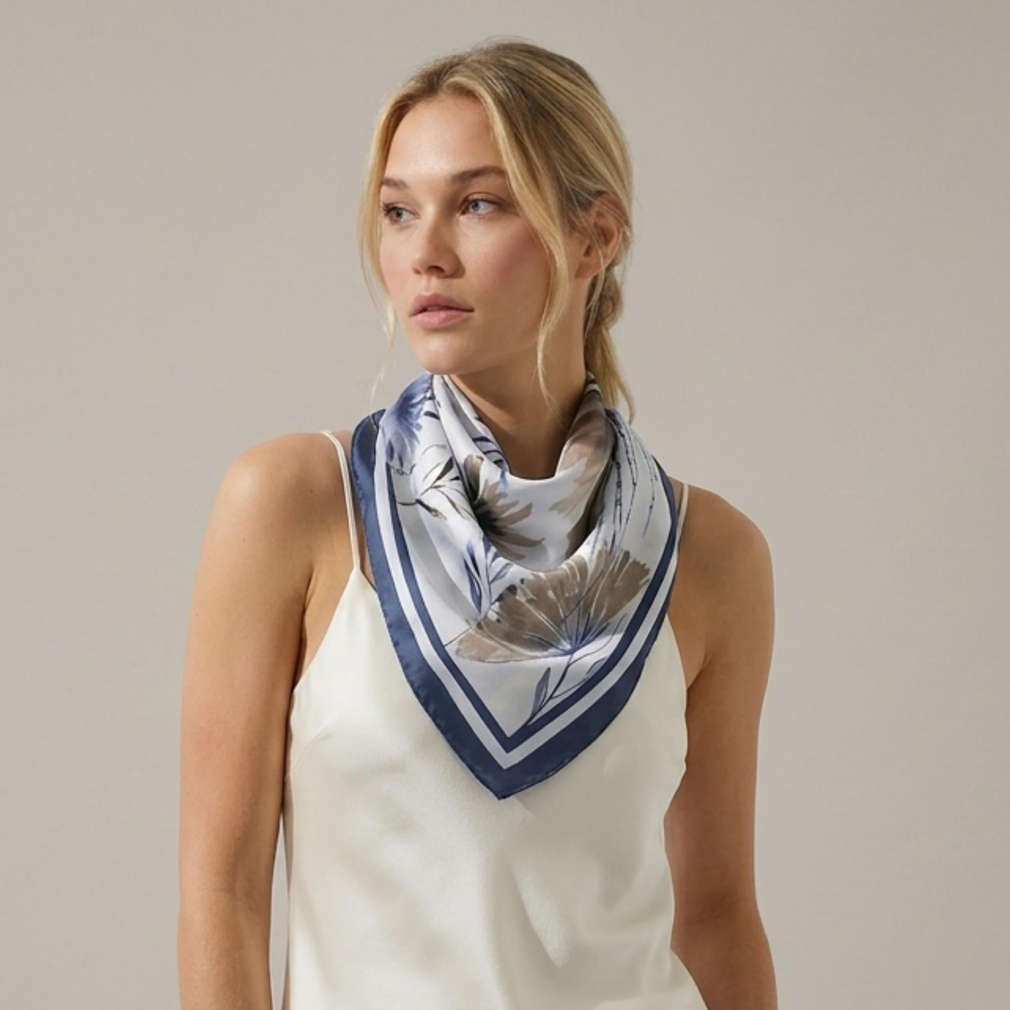Woman wearing a beautiful botanicals silk twill scarf on a plain background
