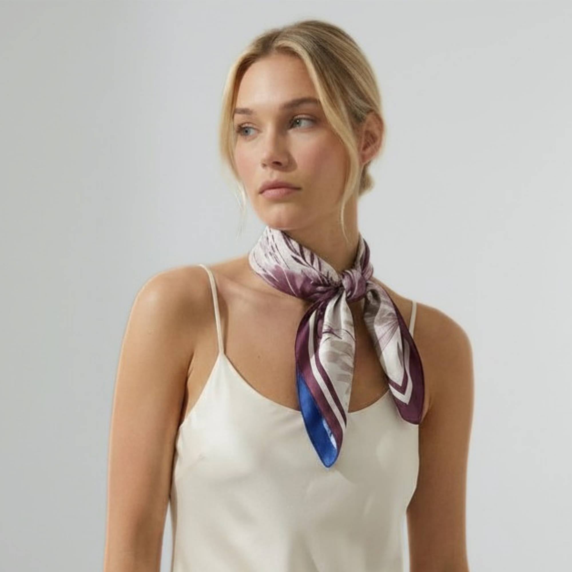 Woman wearing a beautiful botanicals silk twill scarf on a plain background