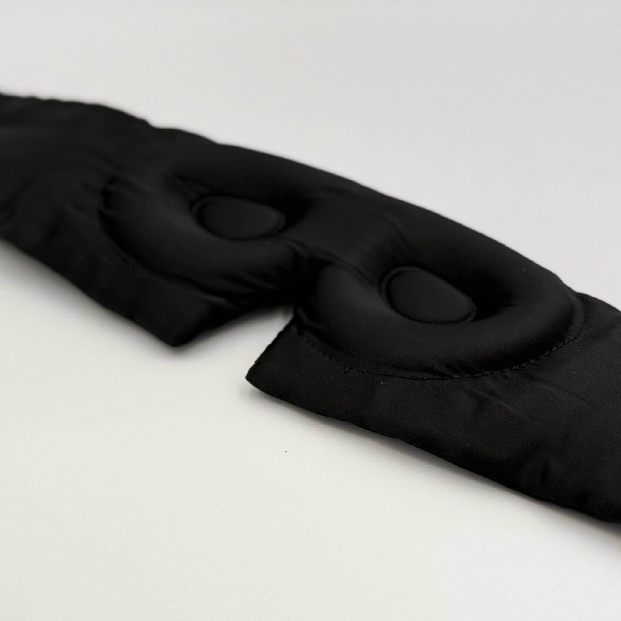 Contoured black silk sleep mask on a white backgrounf