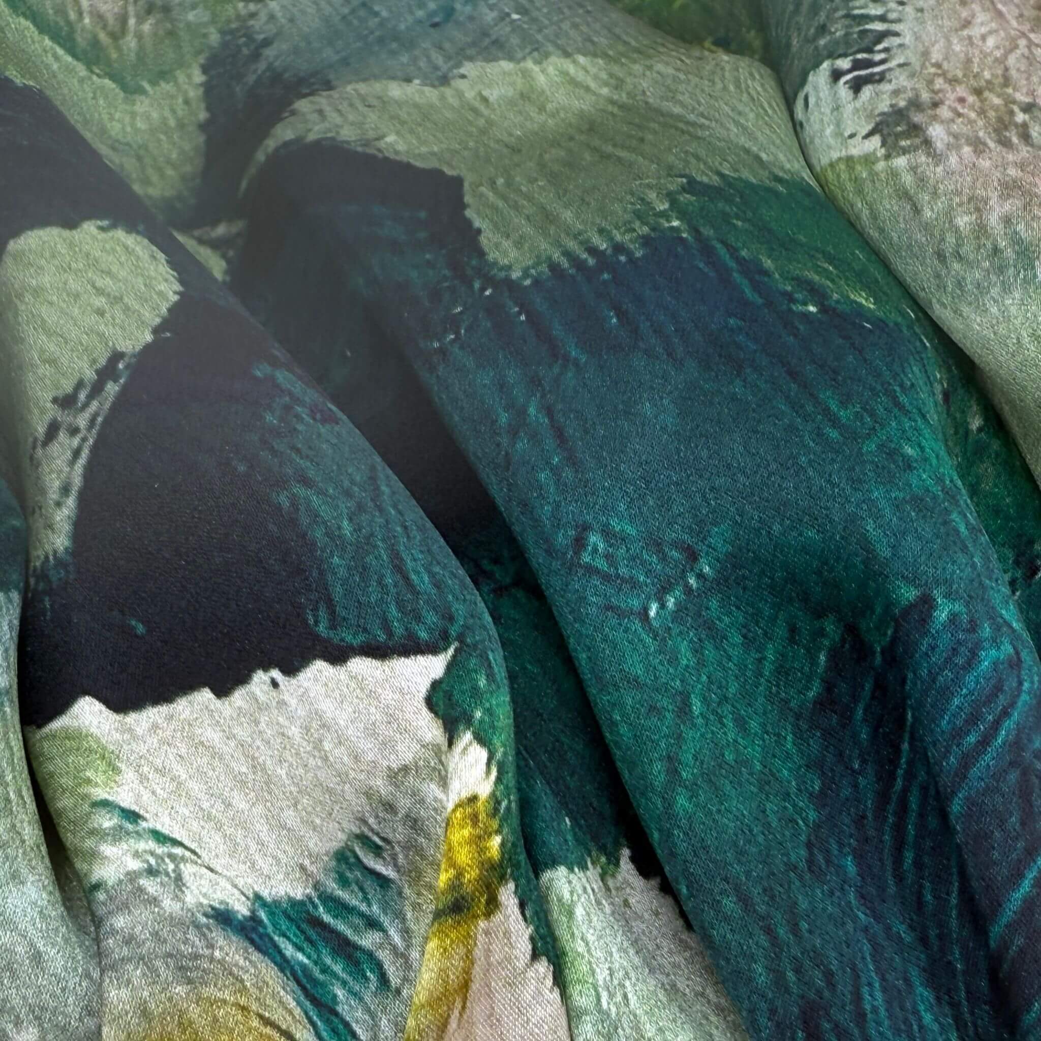 Close-up of a silk fabric with a green and black abstract pattern