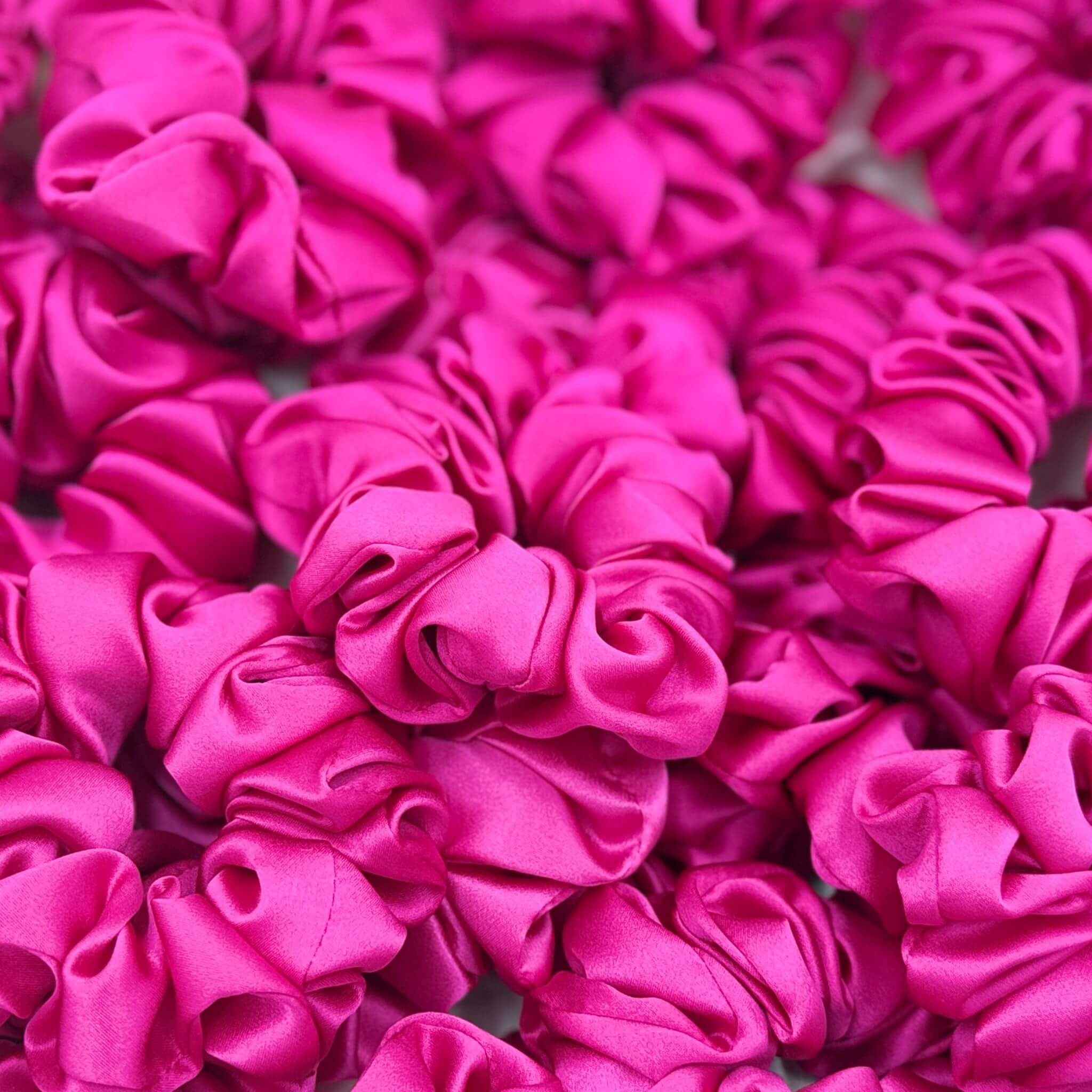 bright pink silk scrunchies in a pile