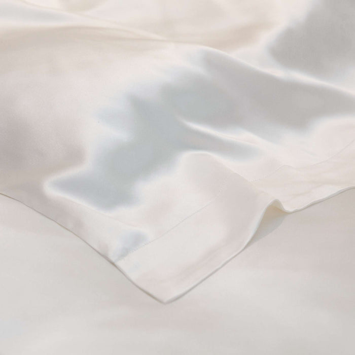 Close-up of a textured ivory silk fabric on a duvet cover on a beige background