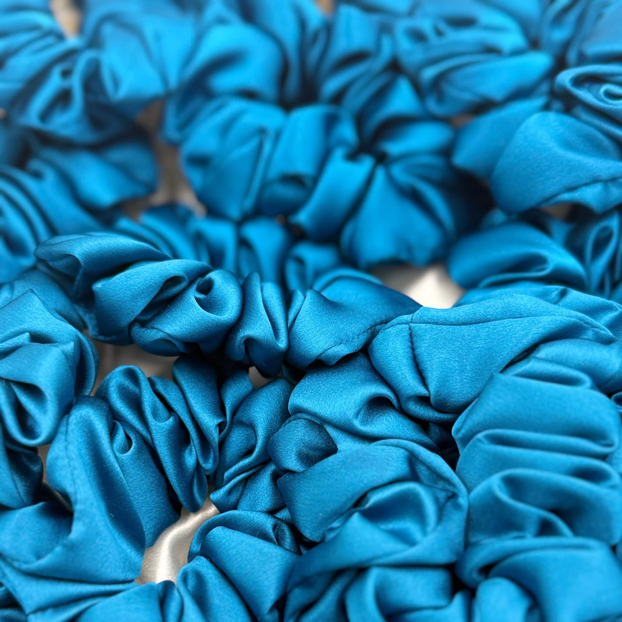crystal teal silk scrunchies in a pile