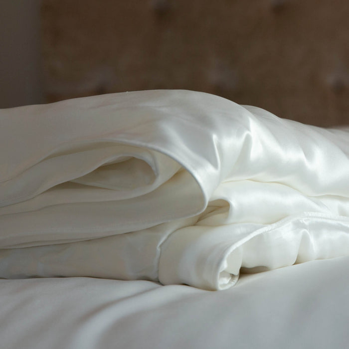 Folded ivory silk duvet sheet on a bed