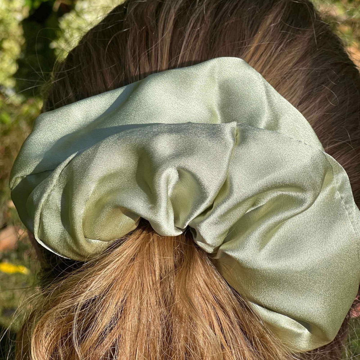 a pistachio green oversized mulberry silk scrunchie in a high ponytail as a close up shot