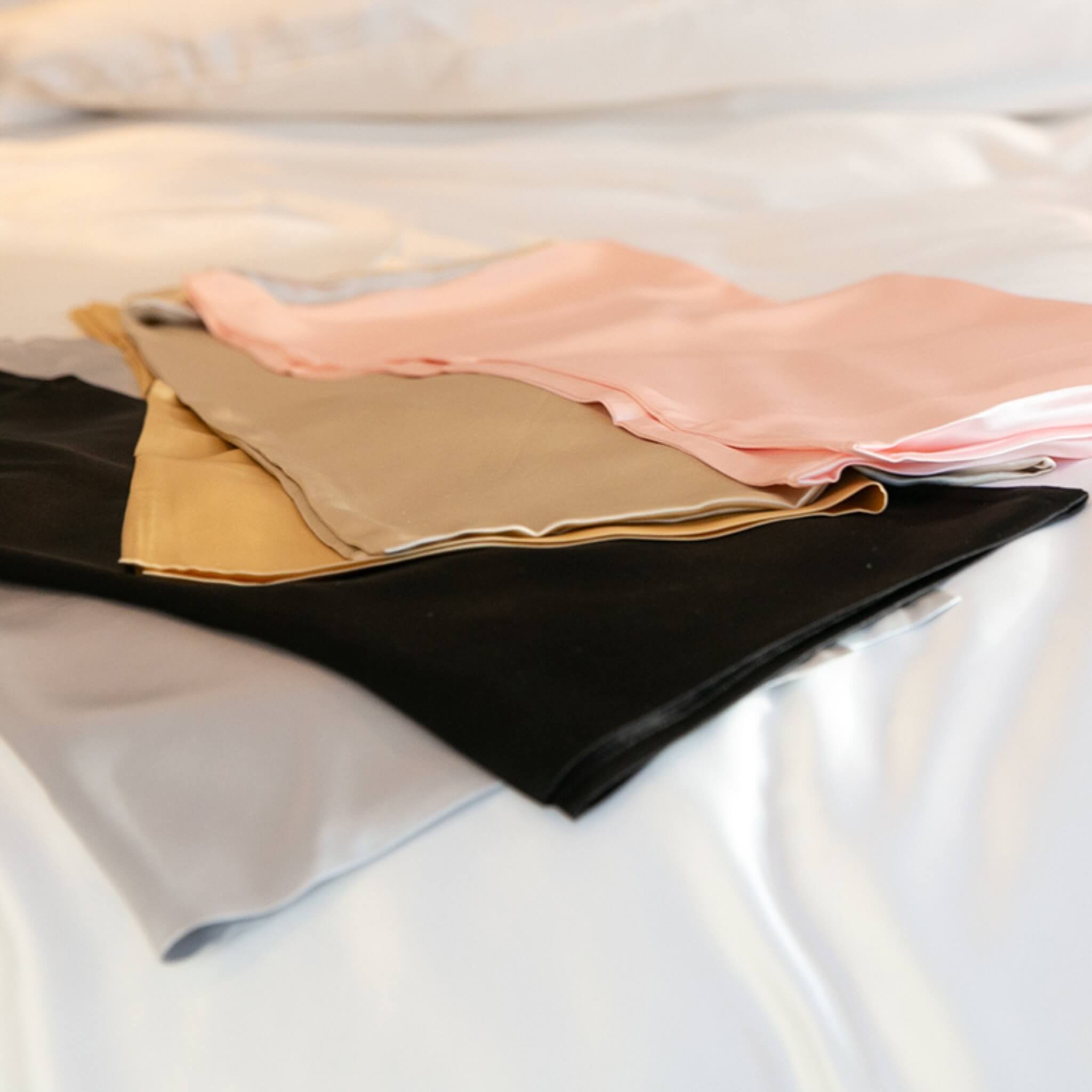 pink, champagne, gold, black and silver 25 momme silk pillowcases folded on top of each other