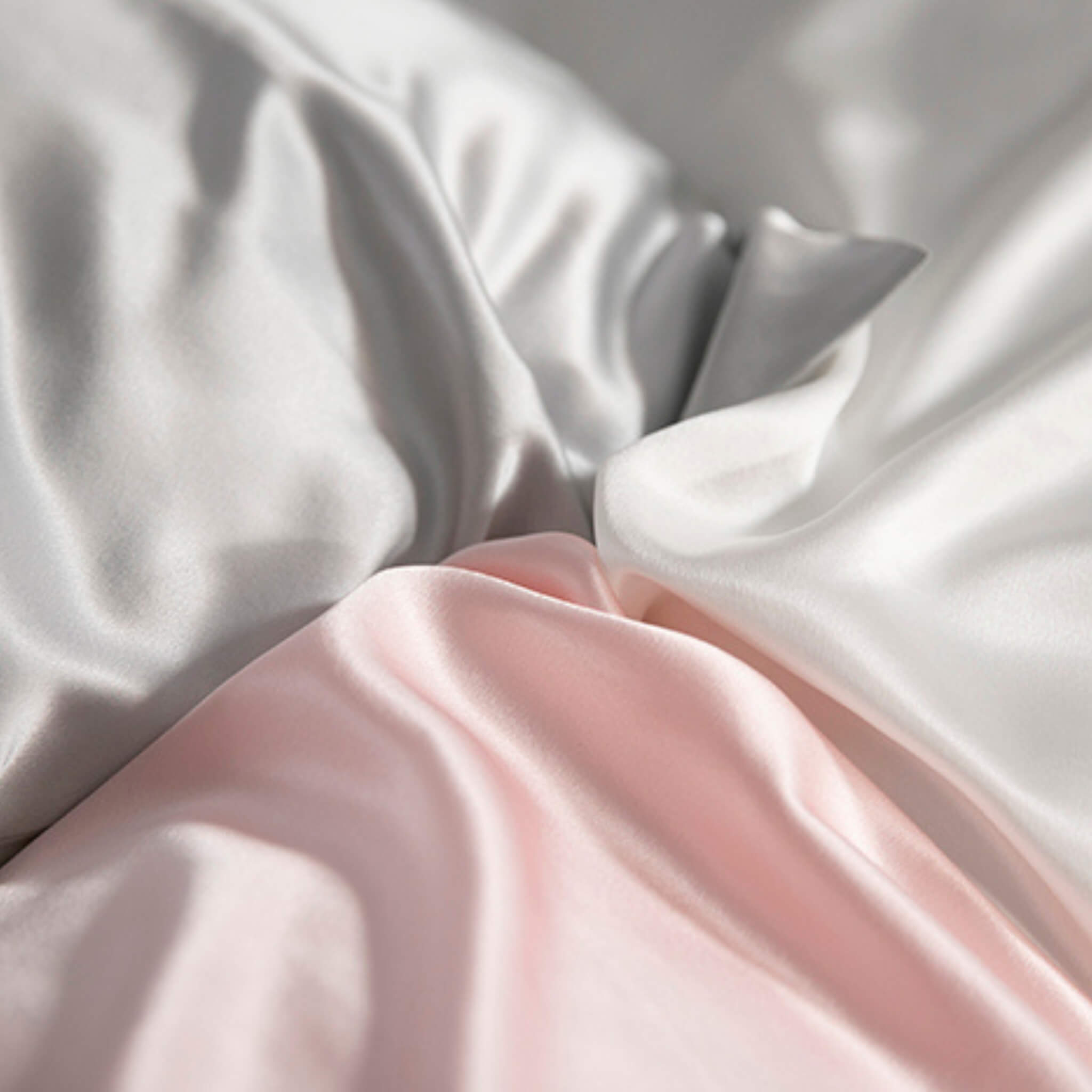 the corners of a silver, ivory and pink 25 momme silk pillowcase