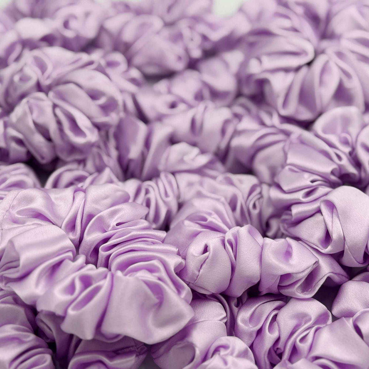 Close-up of multiple lavender purple mulberry silk scrunchies stacked together
