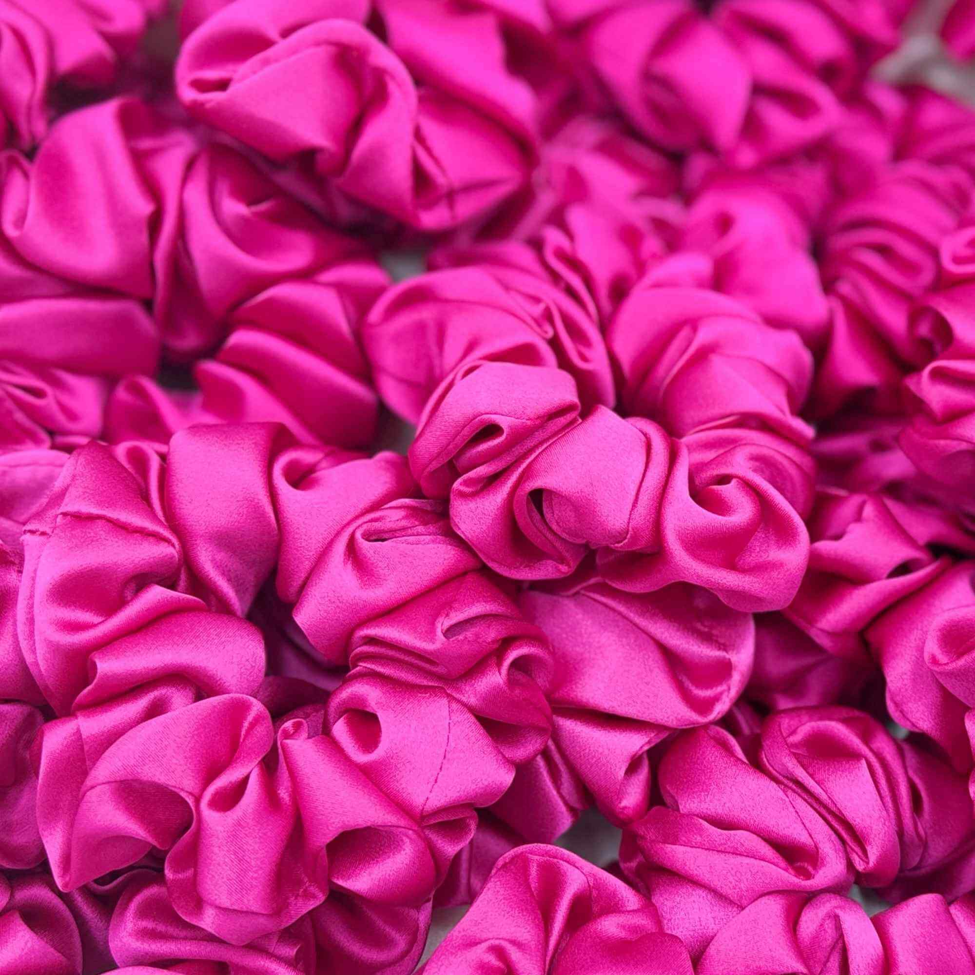 Close-up of multiple bright pink mulberry silk scrunchies.