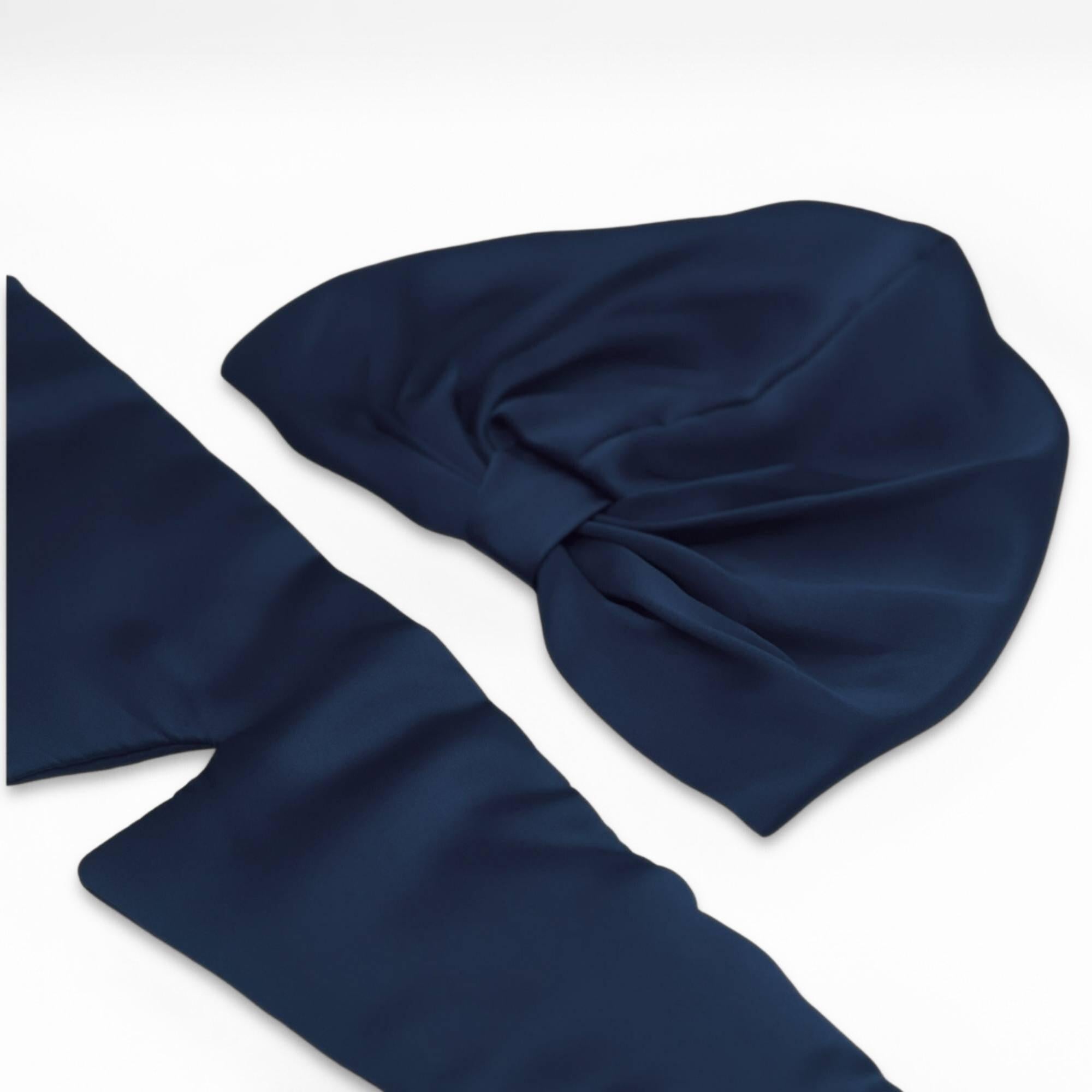 Navy blue silk bonnet and eye mask set lying flat on a white background