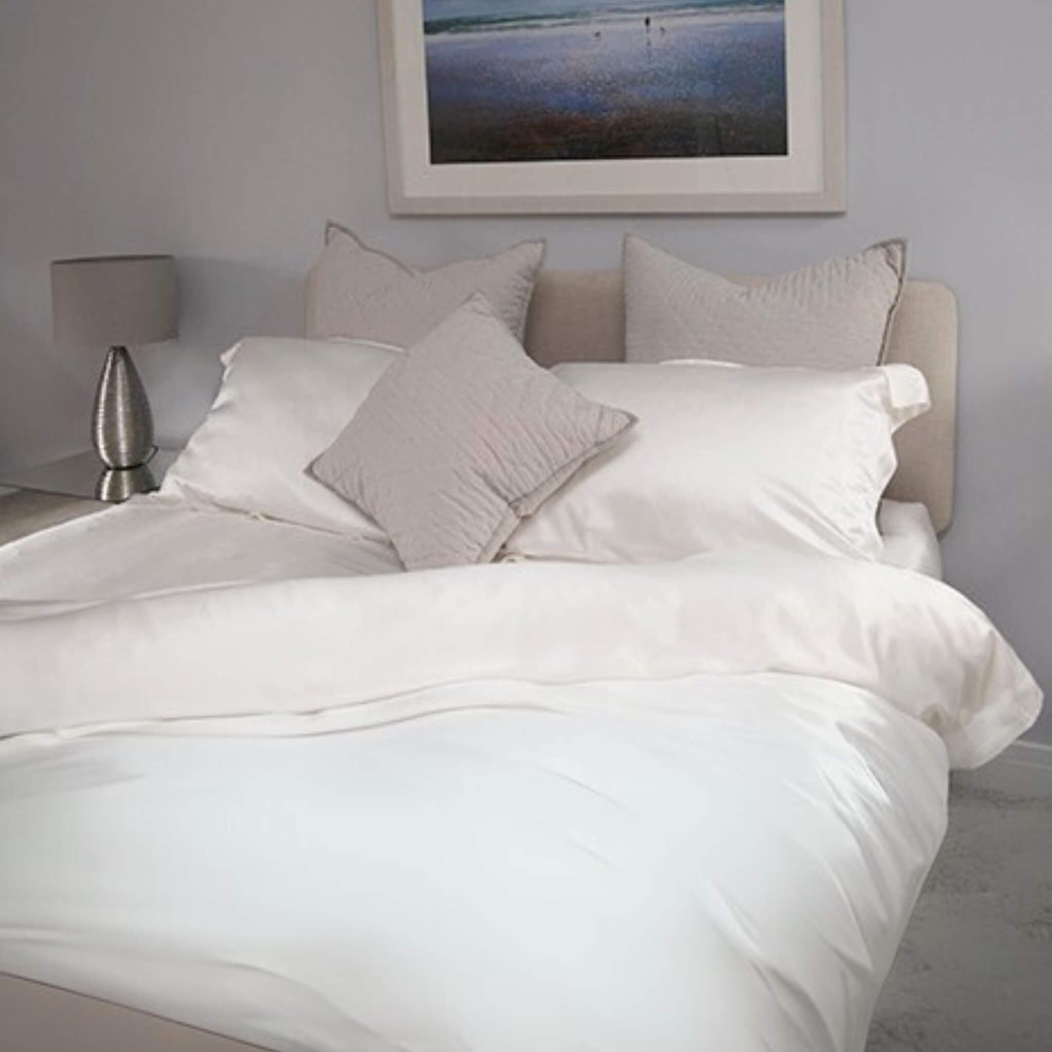 silk bed set in a grey room. the silk duvet cover in folded back at the corner and the picture is taken near the foot of the bed