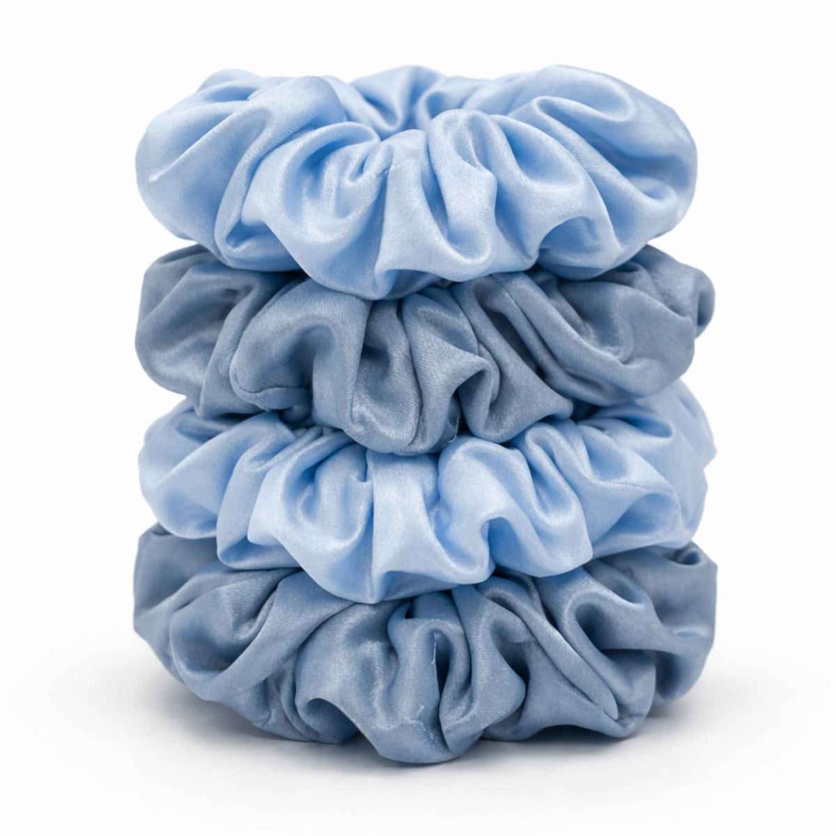 Stack of baby blue and dusty blue silk scrunchies on a white background