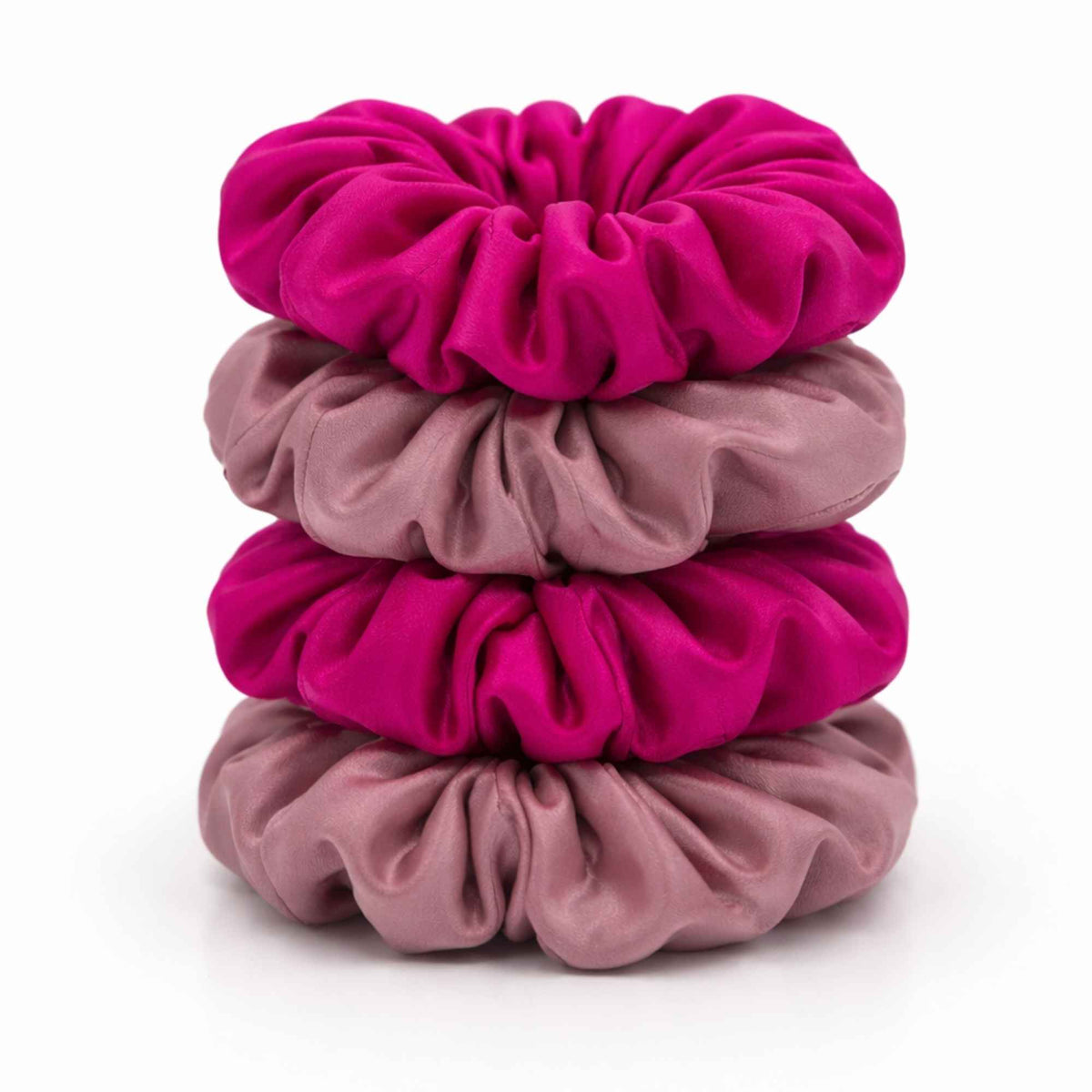 Stack of bright pink and dusty pink silk scrunchies on a white background
