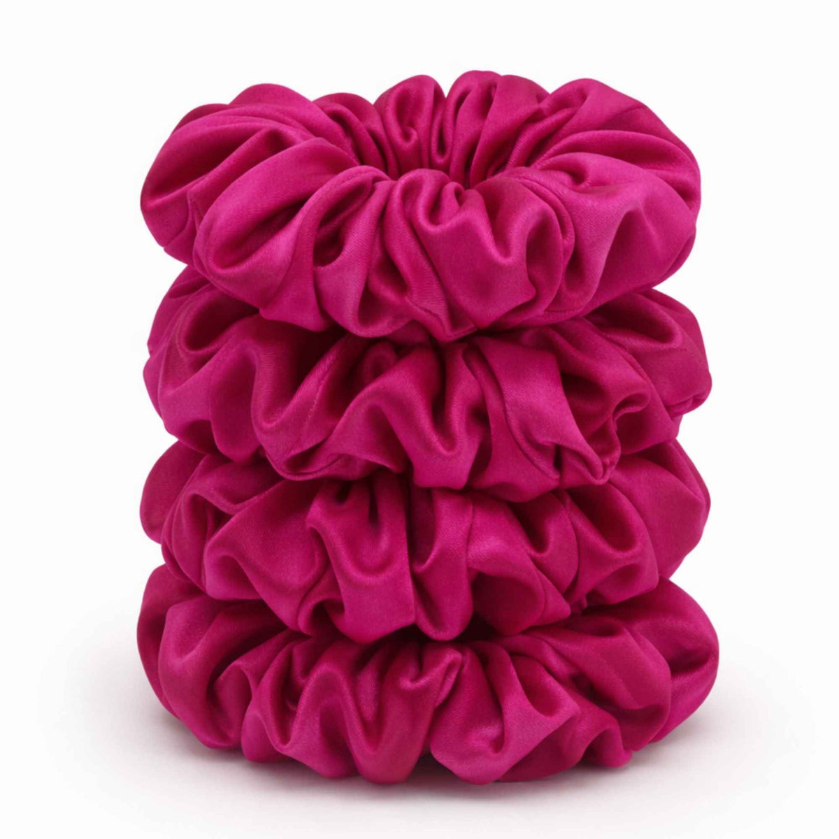 Stack of bright pink silk scrunchies on a white background
