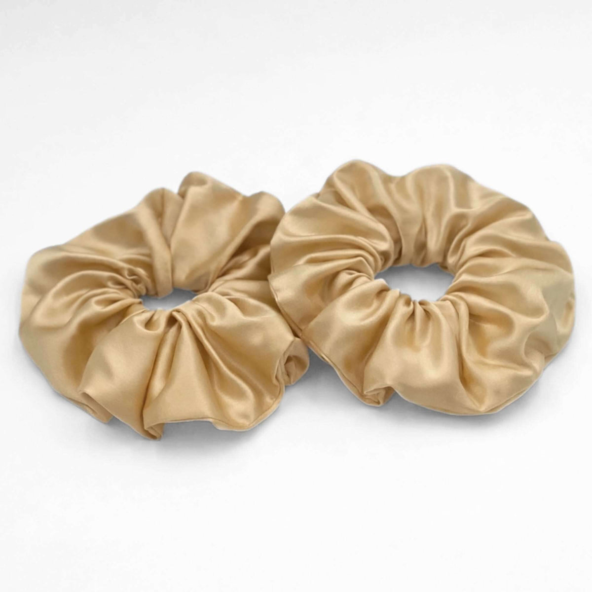 two golden yellow oversized silk scrunchies on a white background