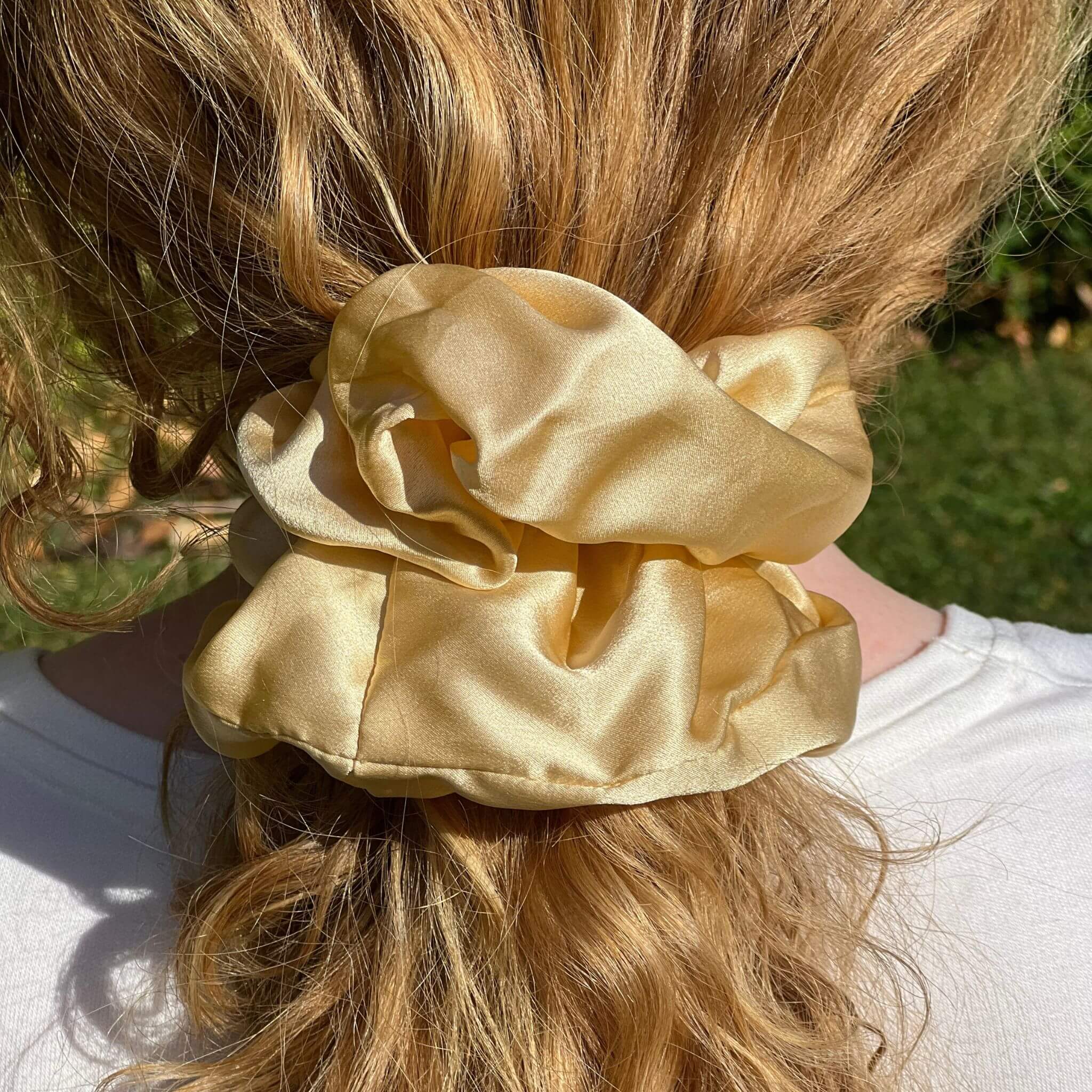 golden yellow oversized silk scrunchie in a low ponytail