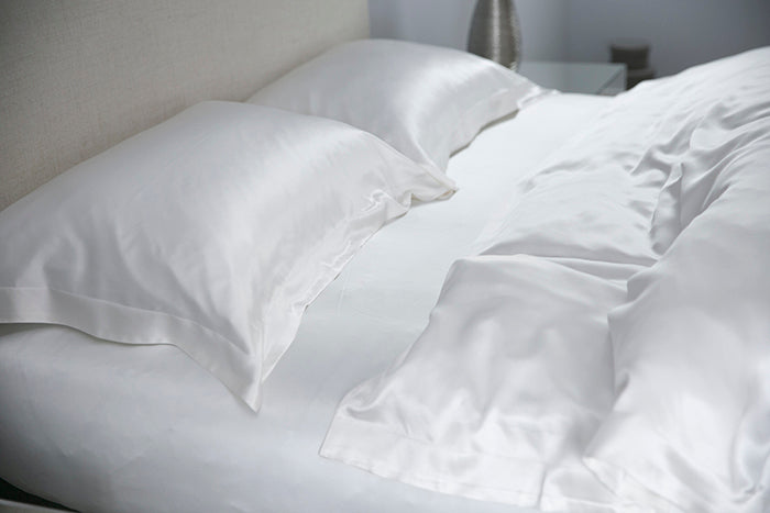 Ivory silk pillows and duvet on a bed in a bedroom setting