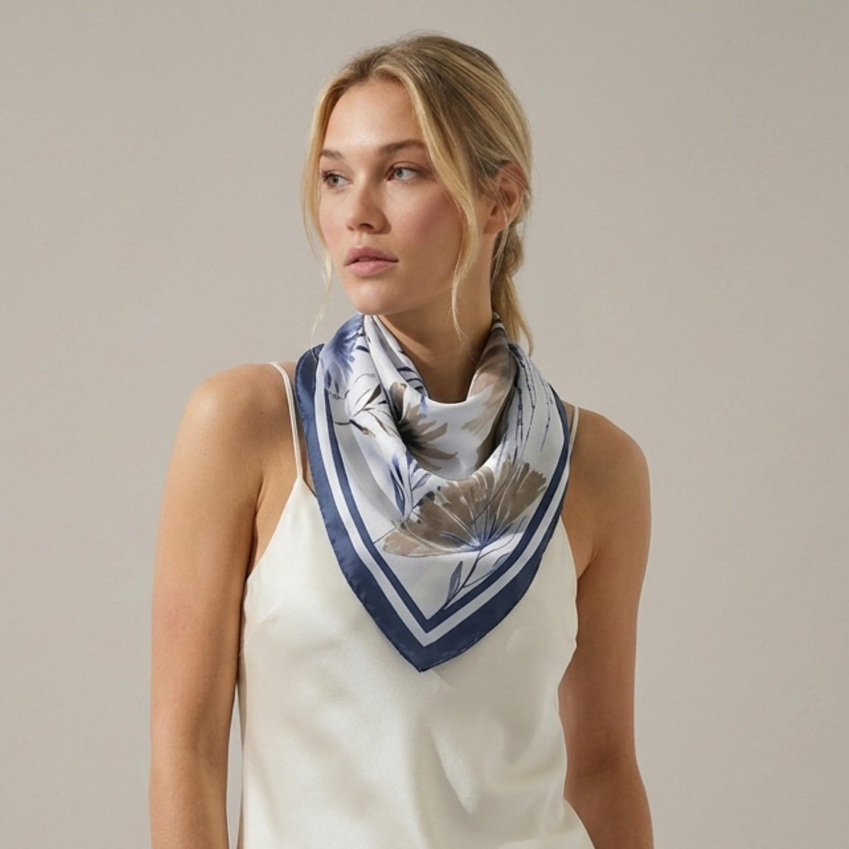 Woman wearing a beautiful botanicals silk twill scarf on a plain background