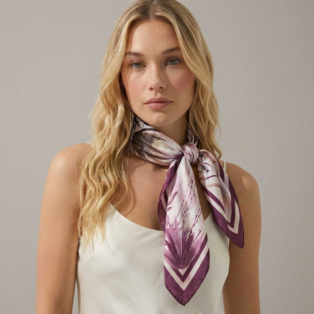 Woman wearing a beautiful botanicals silk twill scarf on a plain background