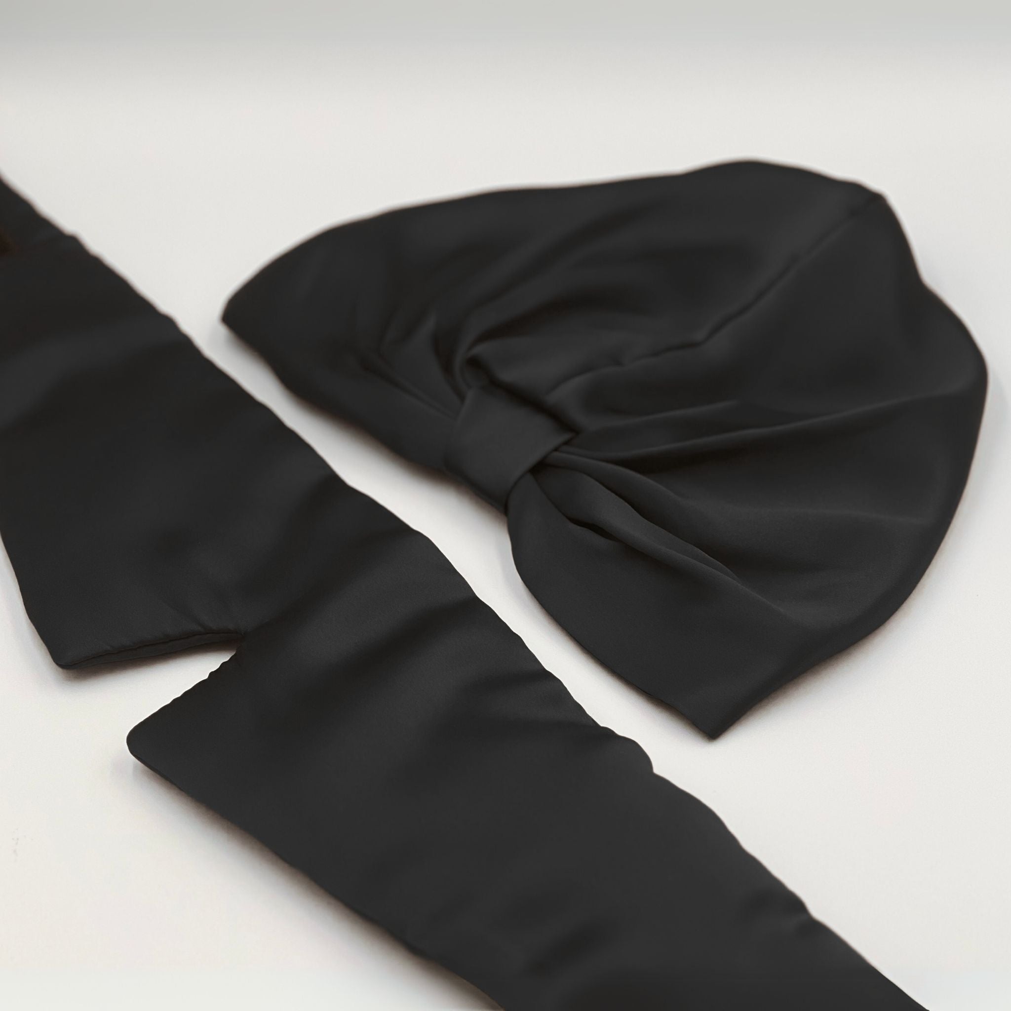 a black silk bonnet and eye mask set, with the eye mask opened out to show its length