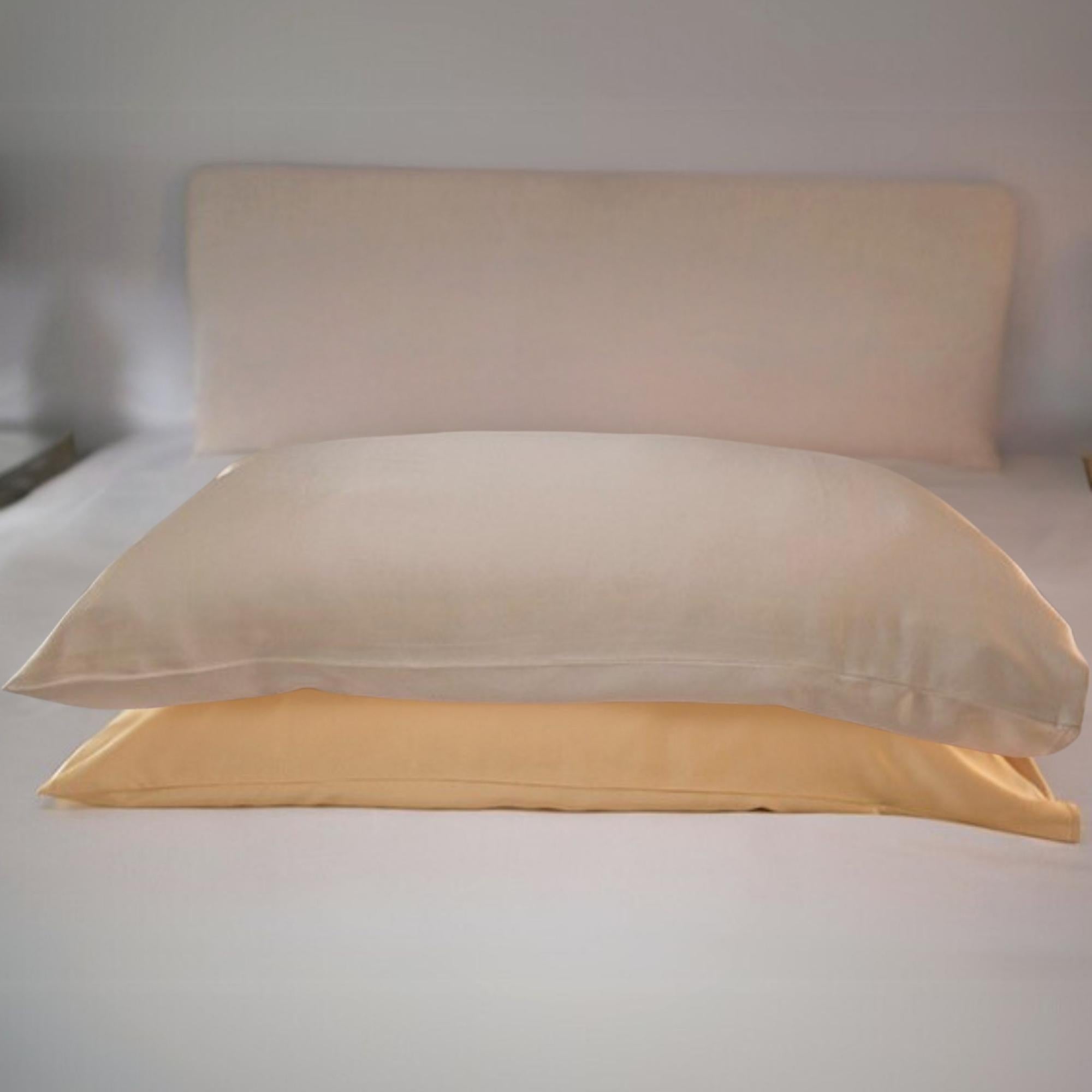 Two silk pillowcases in gold and champagne colors, displayed on a neutral background, with one pillowcase partially covering the other.