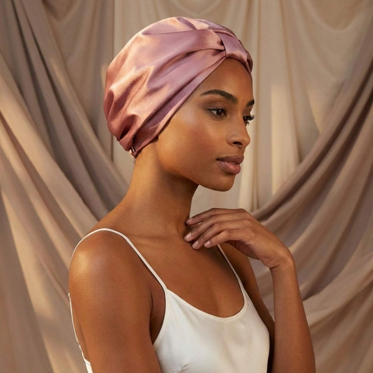 Woman wearing a dusty pink mulberry silk bonnet against a beige background
