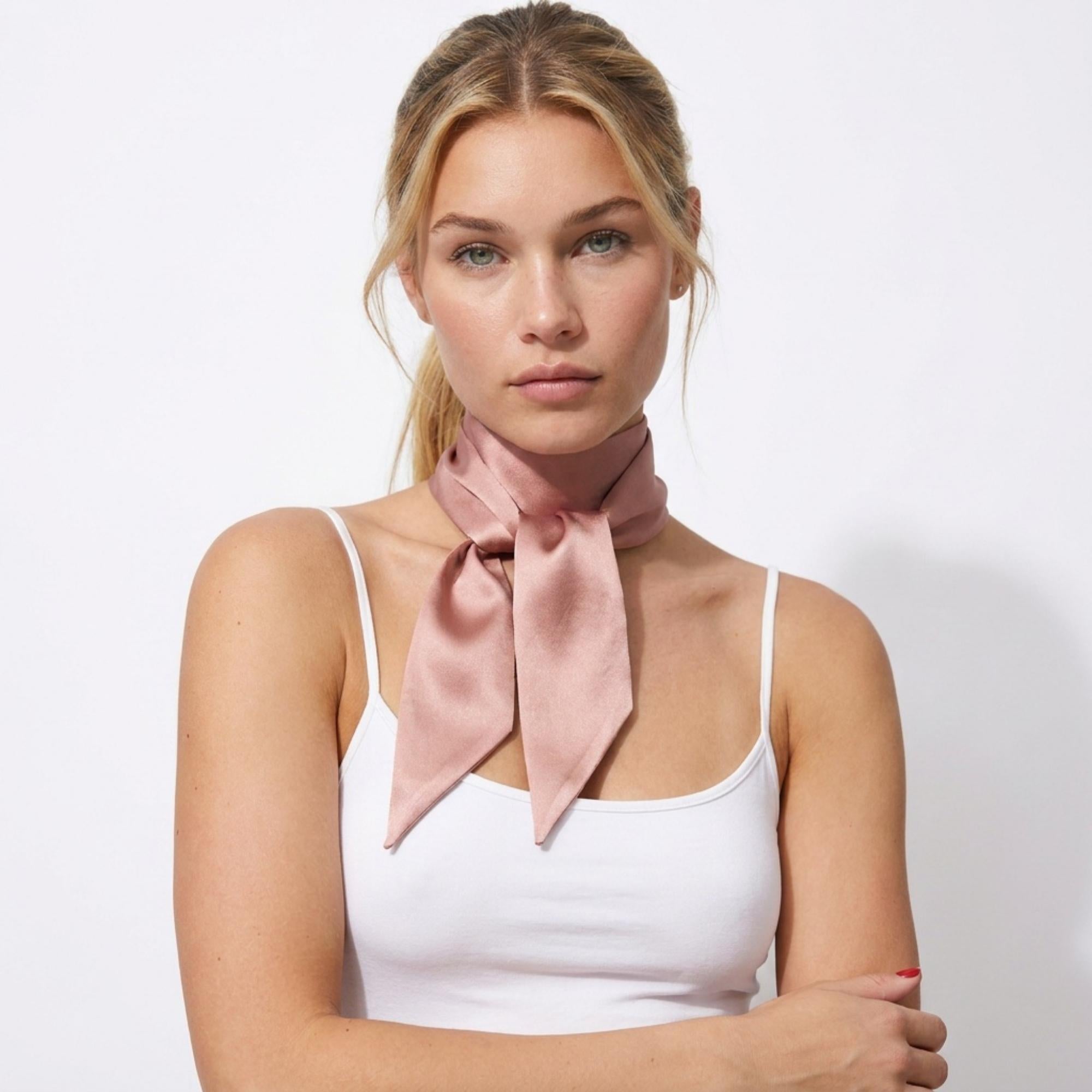 Woman wearing a dusty pink silk skinny scarf around her neck on a white background