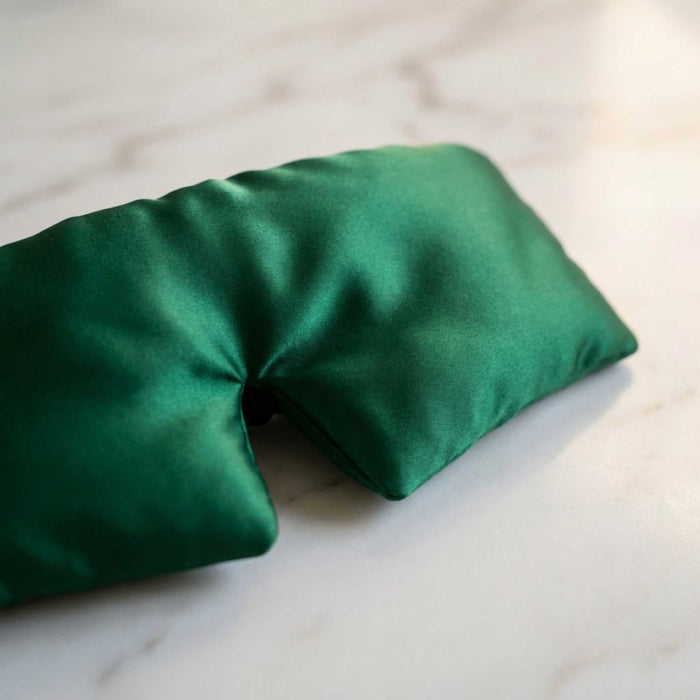 forest green silk eye mask on a plain surface
