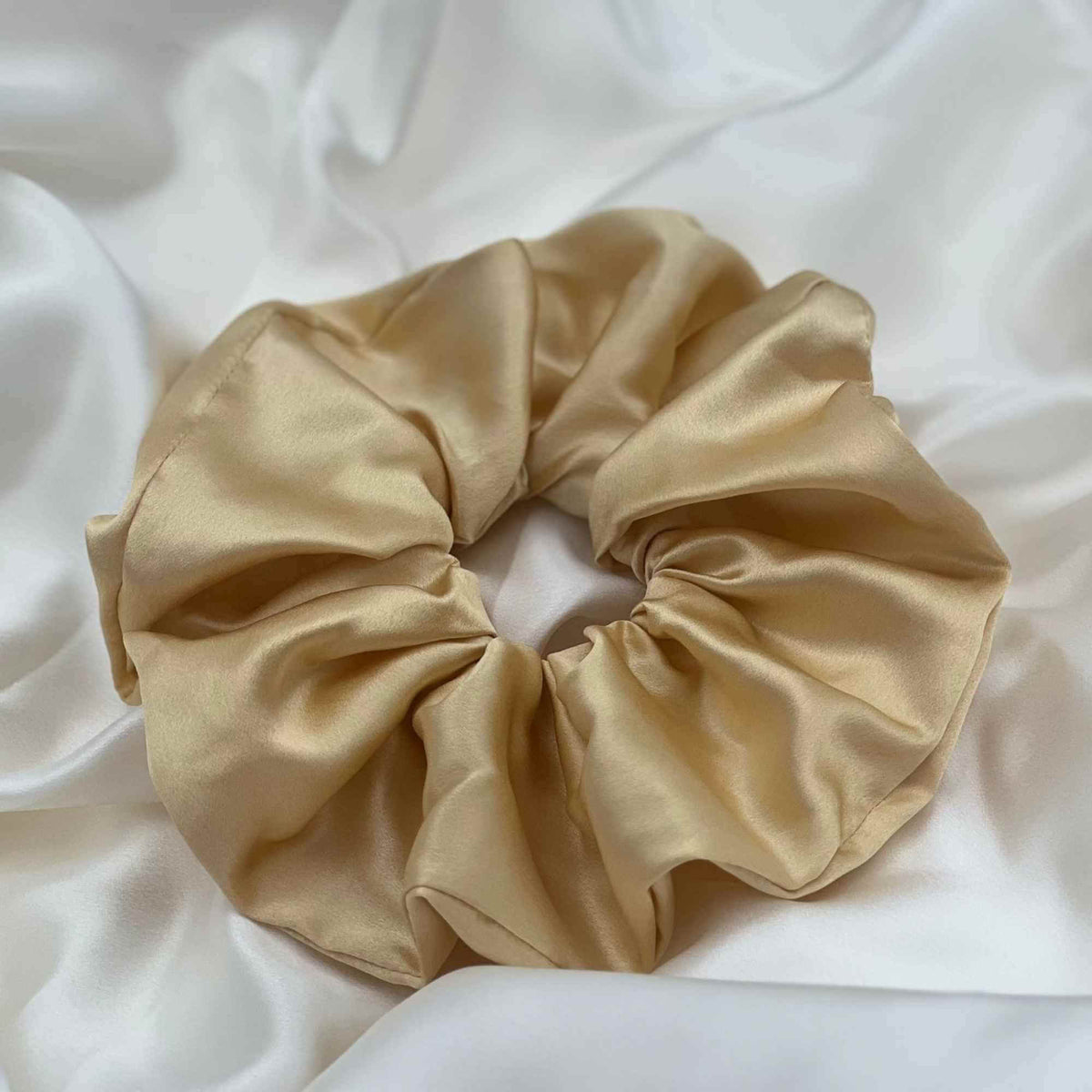 golden yellow oversized silk scrunchie on an ivory silk piece of fabric