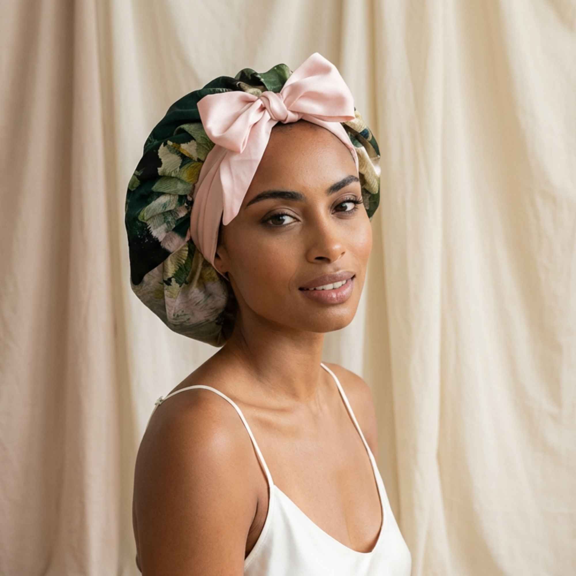 Woman wearing a floral silk bonnet with a pink bow against a beige curtain background