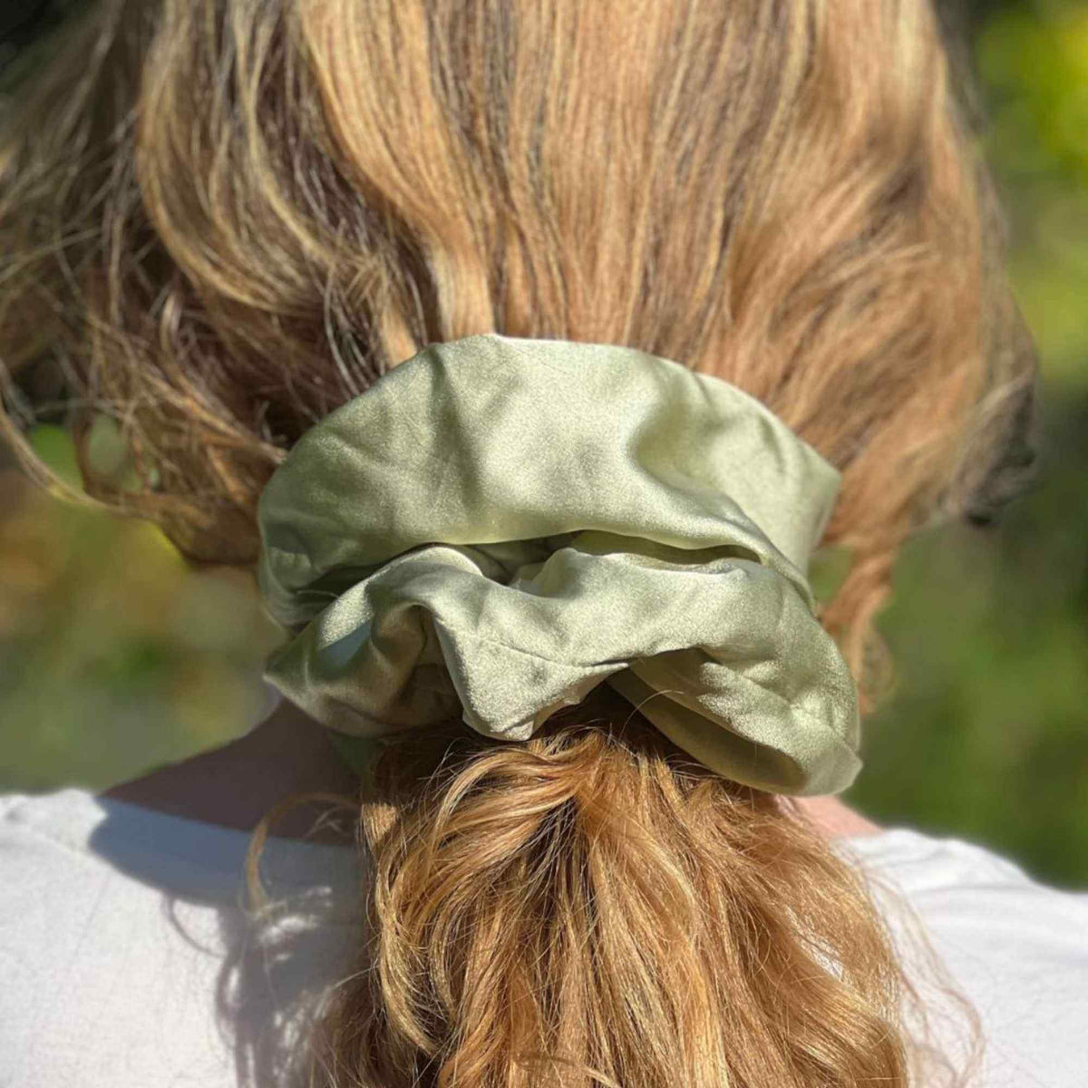 a pistachio green oversized mulberry silk scrunchie in a low ponytail shot from the back