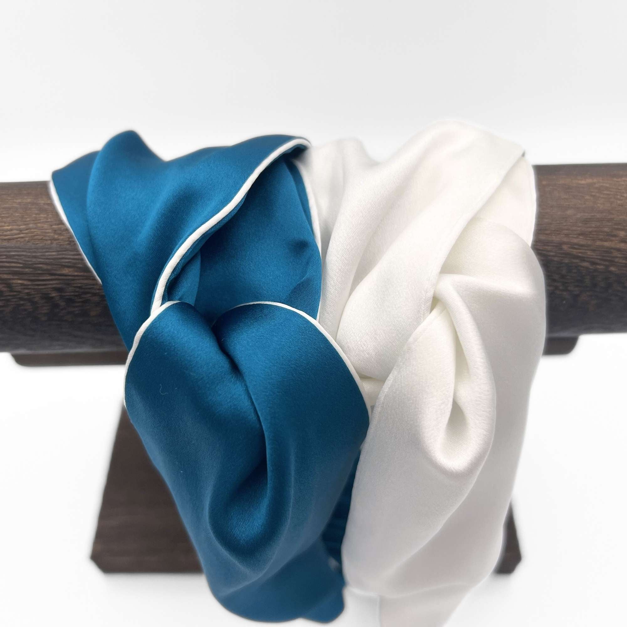 Blue and white silk headbands on a wooden stand against a white background