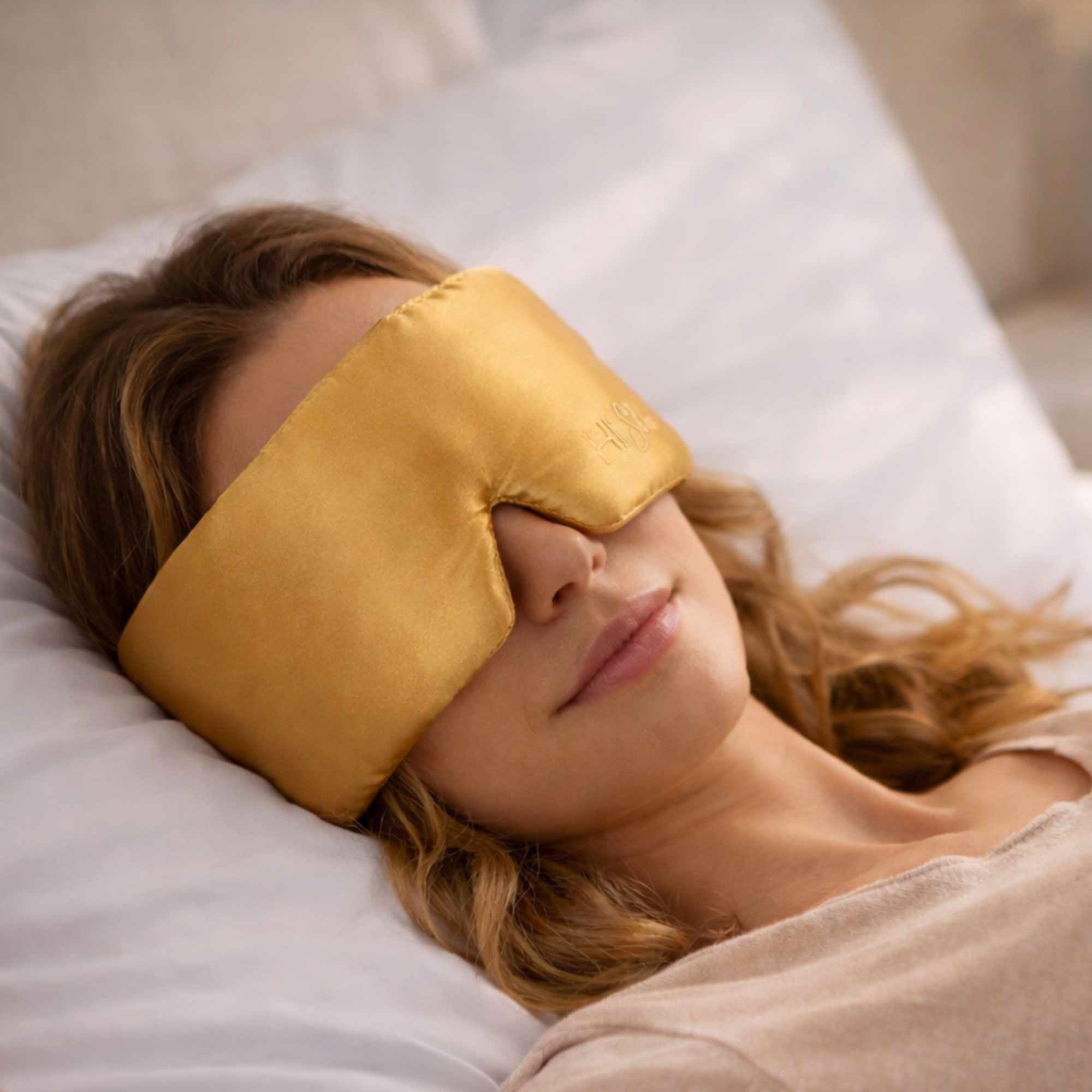 Woman wearing a yellow sleep mask lying on a pillow.