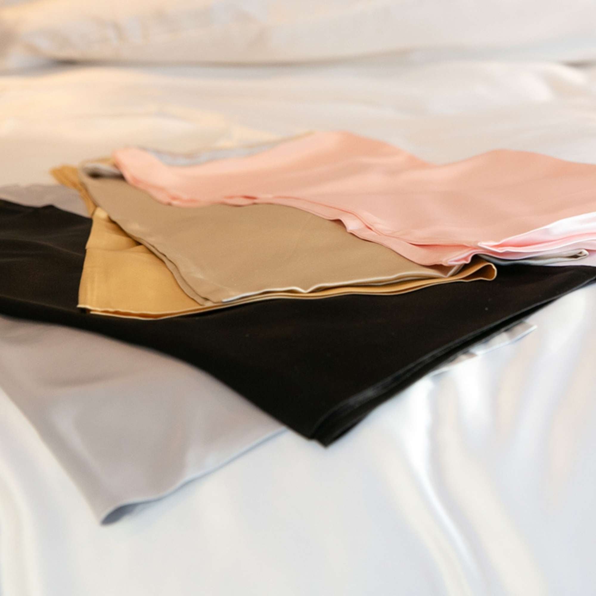 pink, champagne, gold, black and silver 25 momme silk pillowcases folded on top of each other