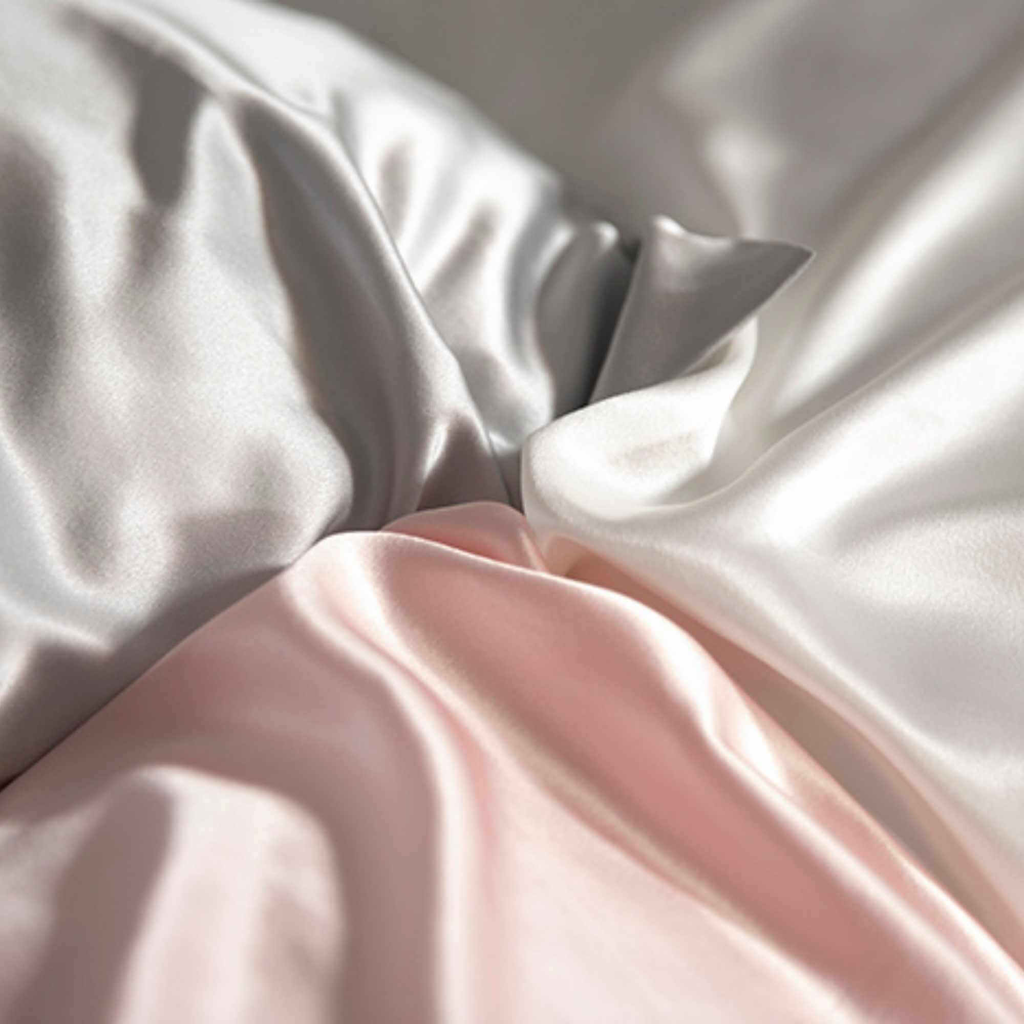 the corners of a silver, ivory and pink 25 momme silk pillowcase