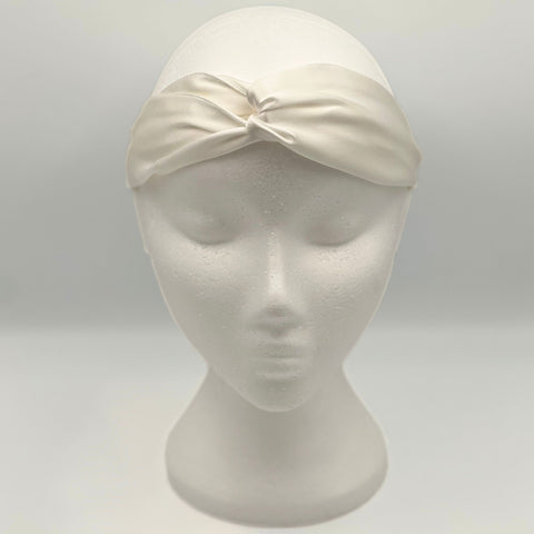 An ivory silk headband on a mannequins head. The front shows a tie 