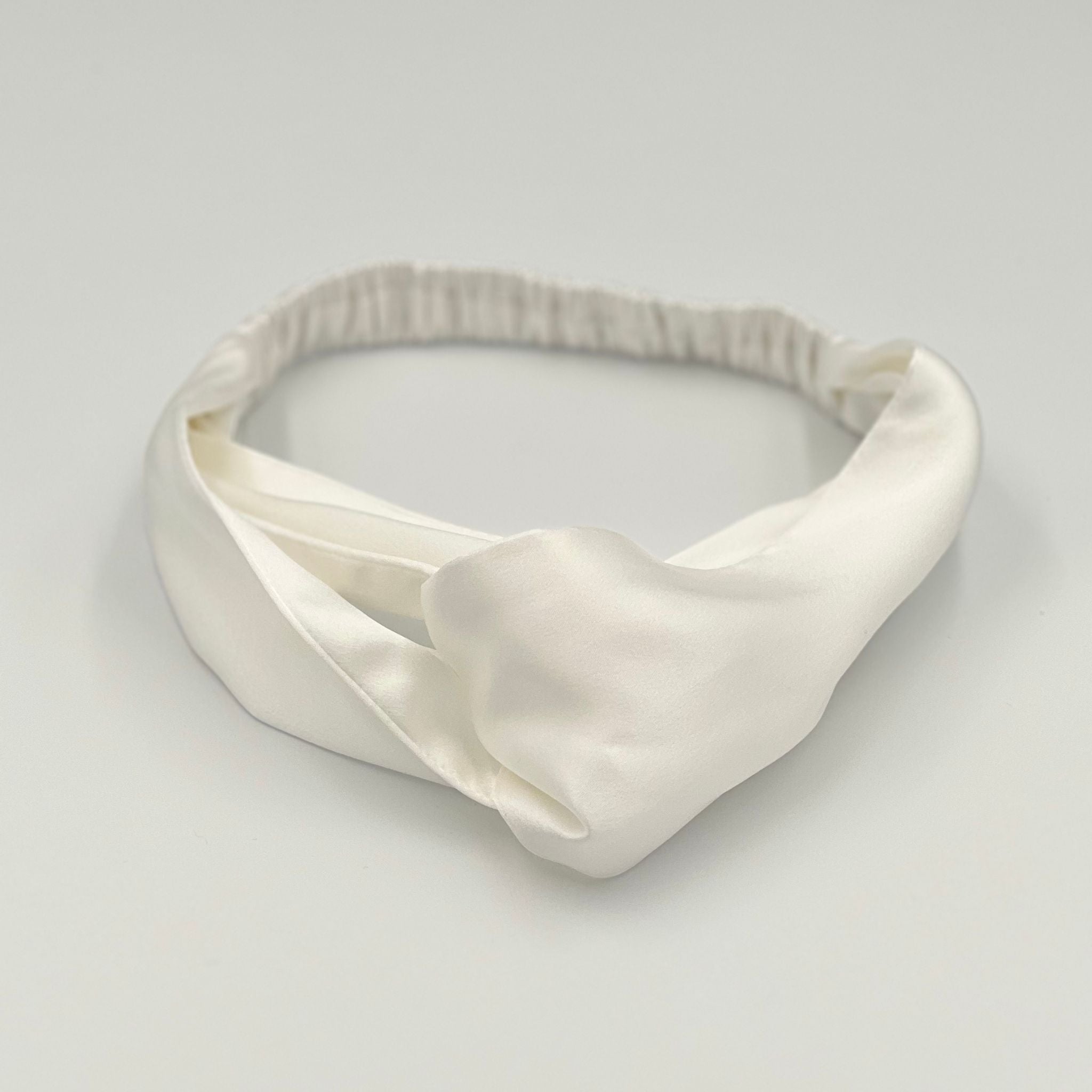 An ivory silk headband lying flat