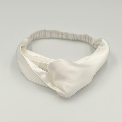 An ivory silk headband lying flat