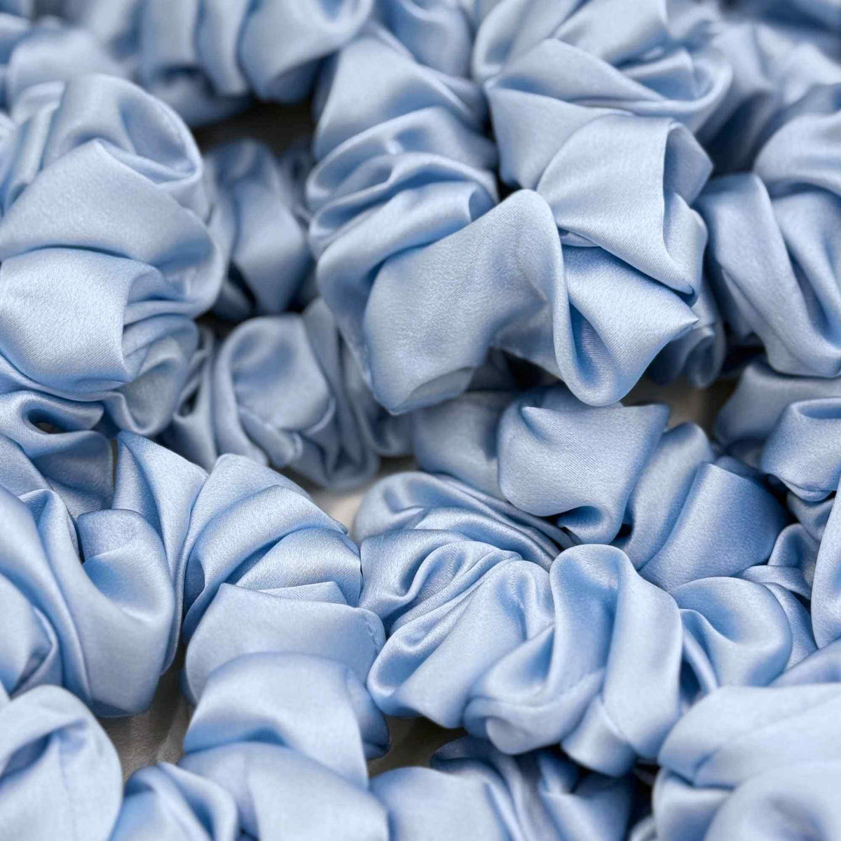 Close-up of multiple baby blue mulberry silk scrunchies.