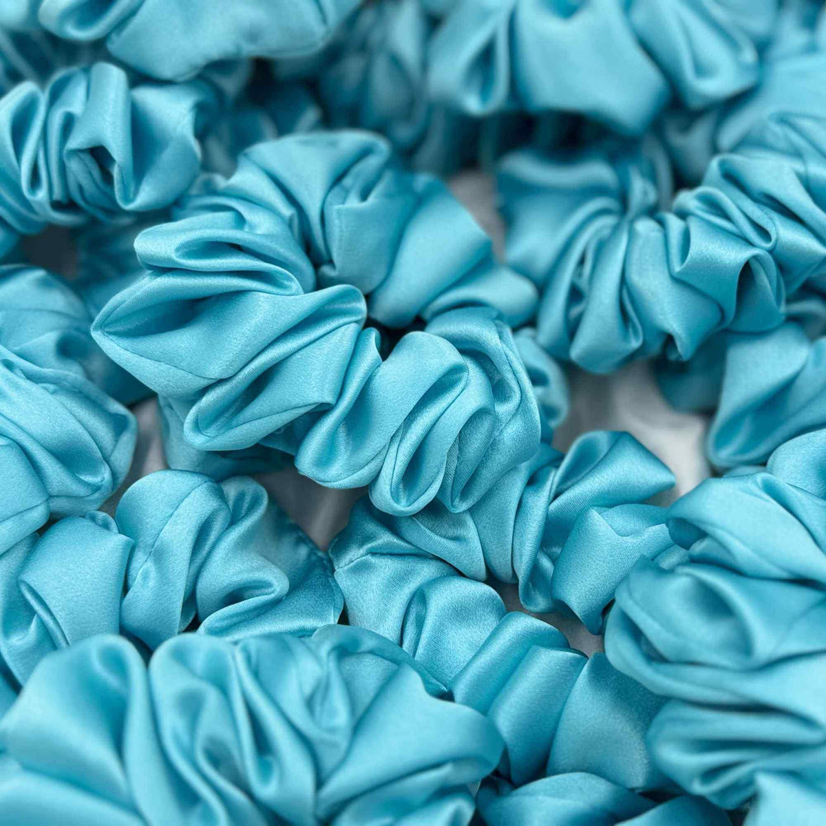 Close-up of multiple ronins egg blue mulberry silk scrunchies.