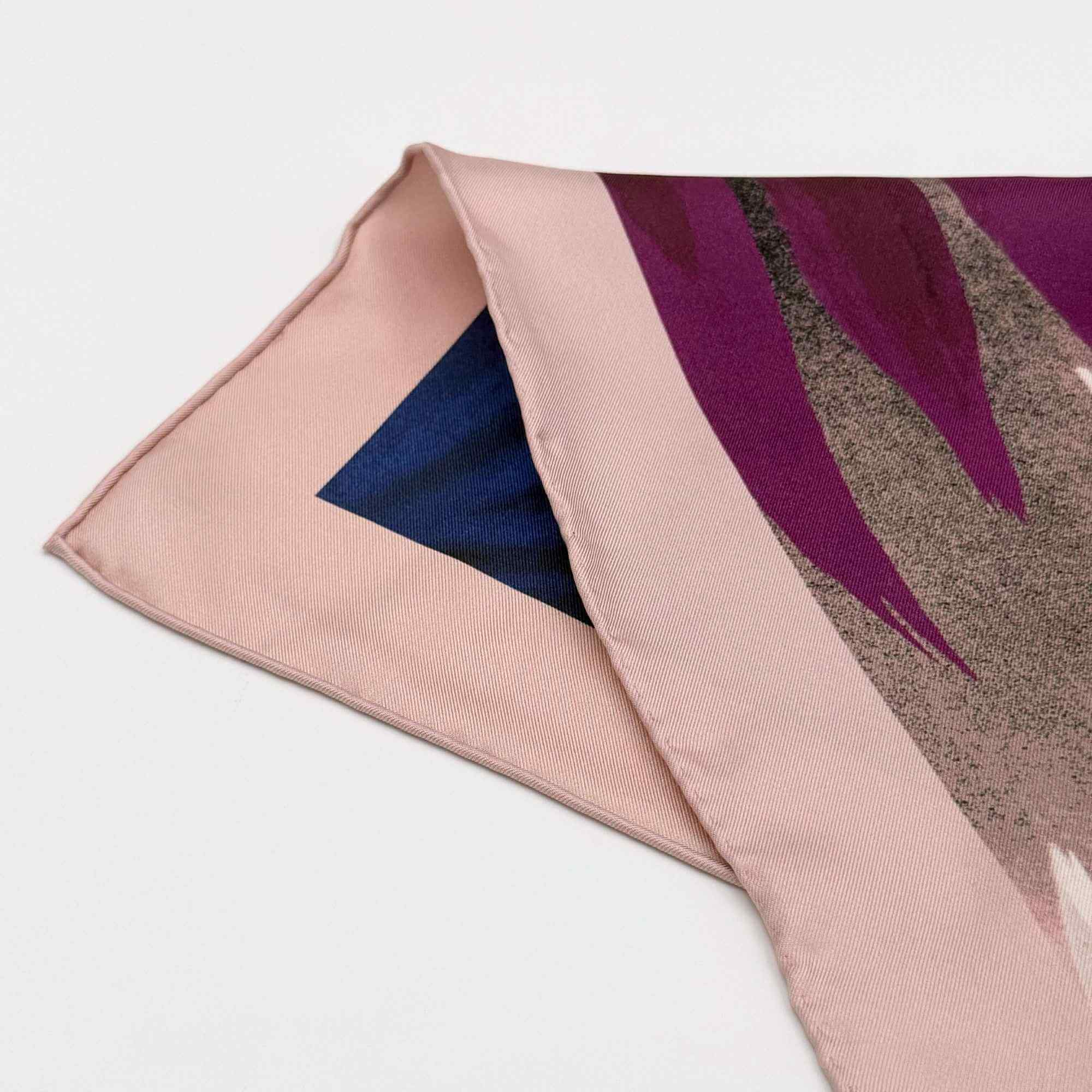 Close-up of a pink silk twill scarf with a floral pattern on a white background