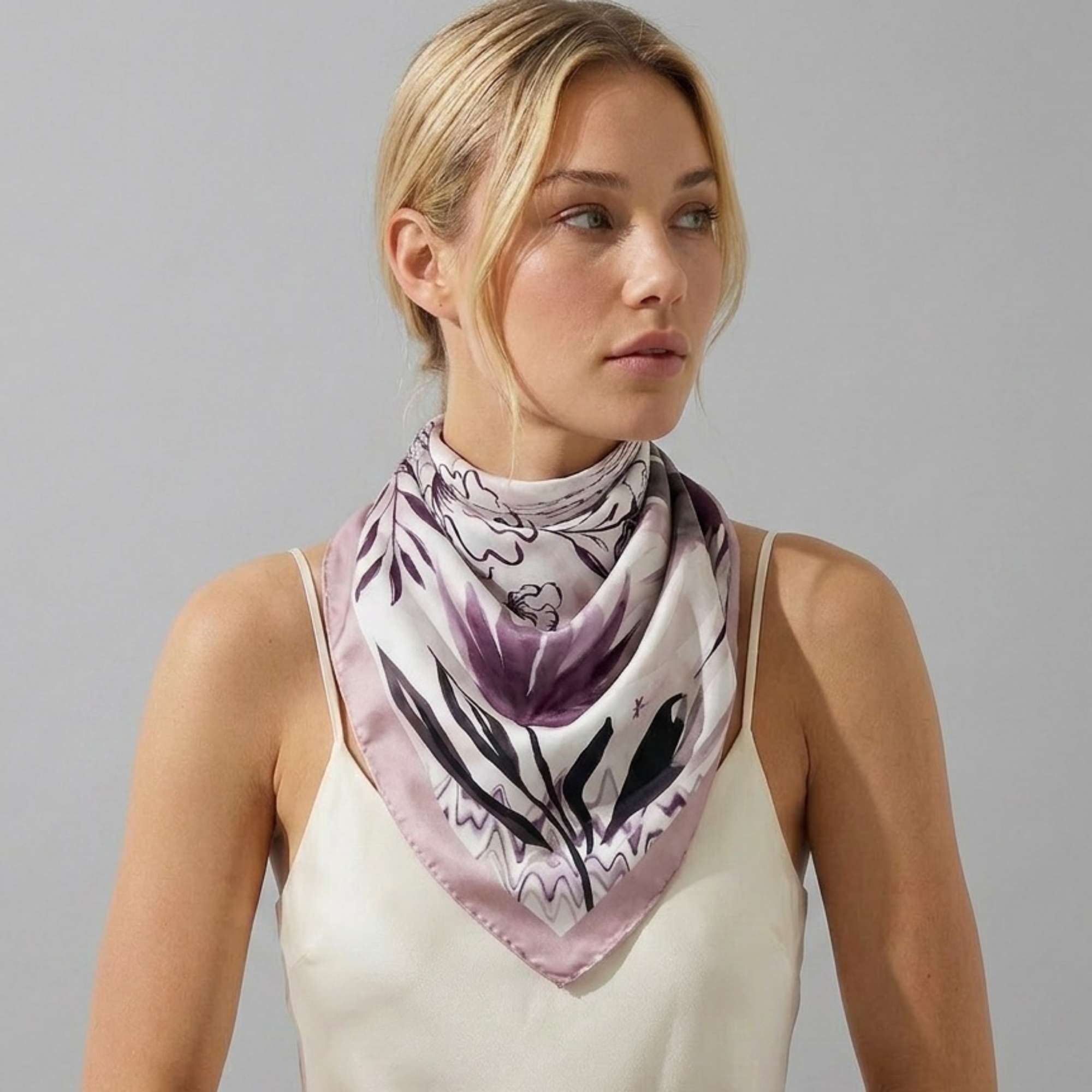 Woman wearing a petals and palms silk twill scarf on a plain background