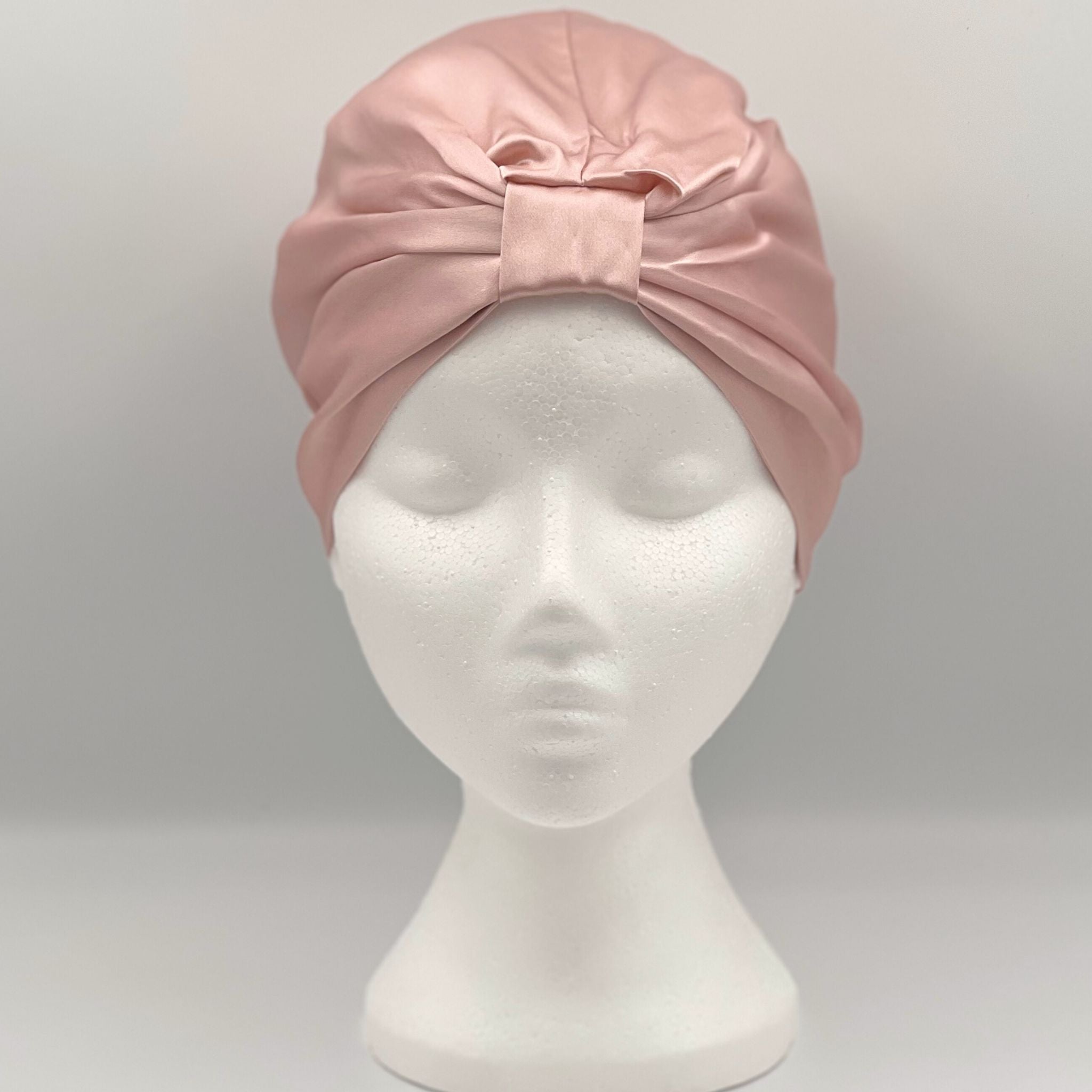 Front view of a pink silk bonnet on a mannequin