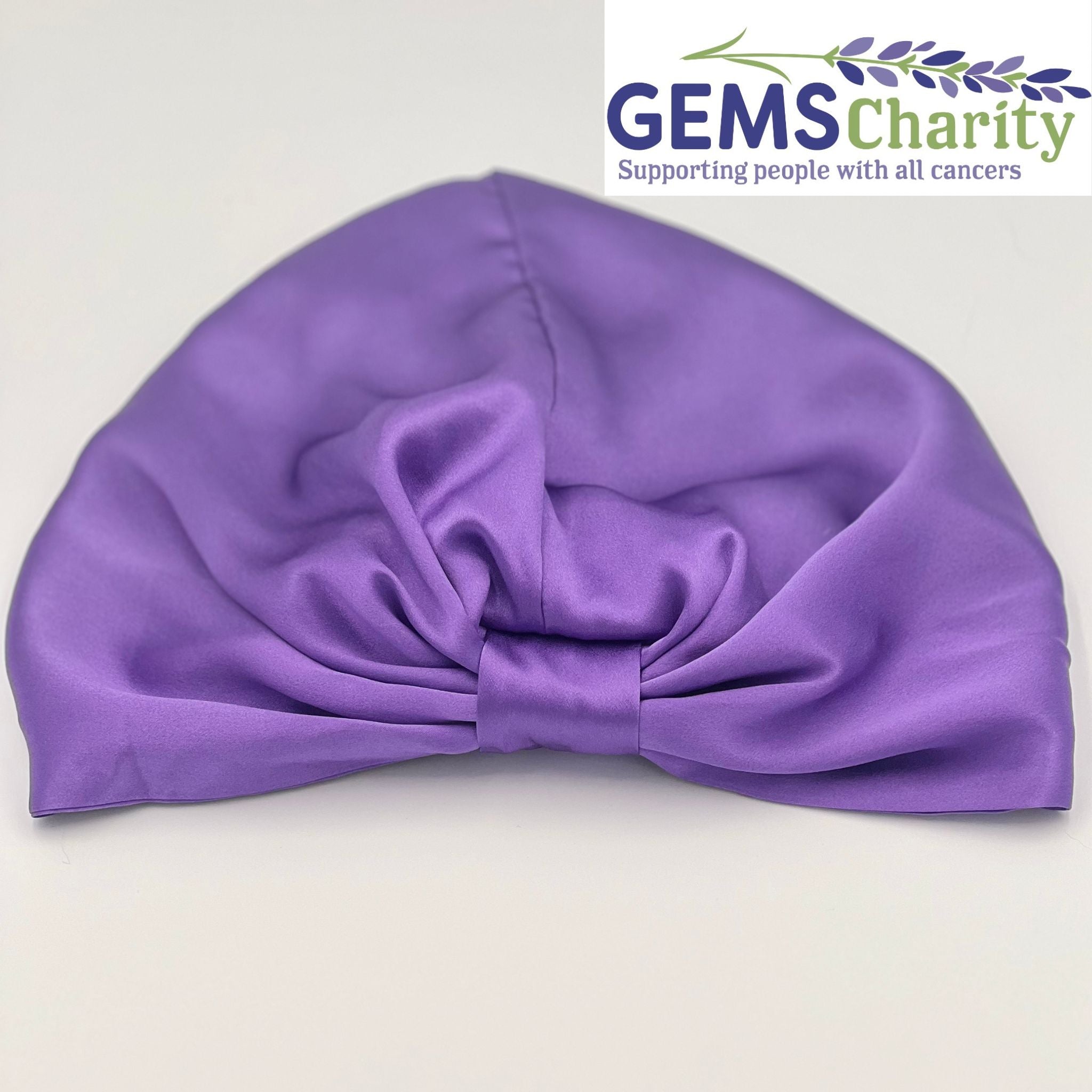 Purple silk bonnet laying flat with GEMS Charity logo in the corner