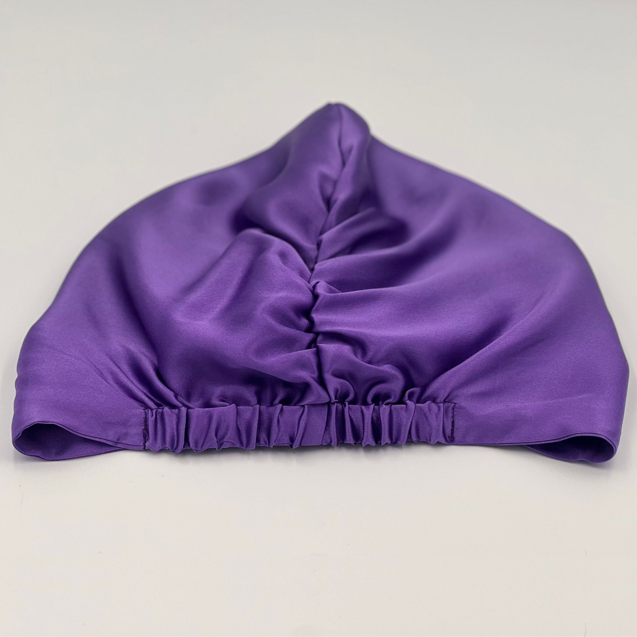 Back view of a purple silk bonnet laying flat